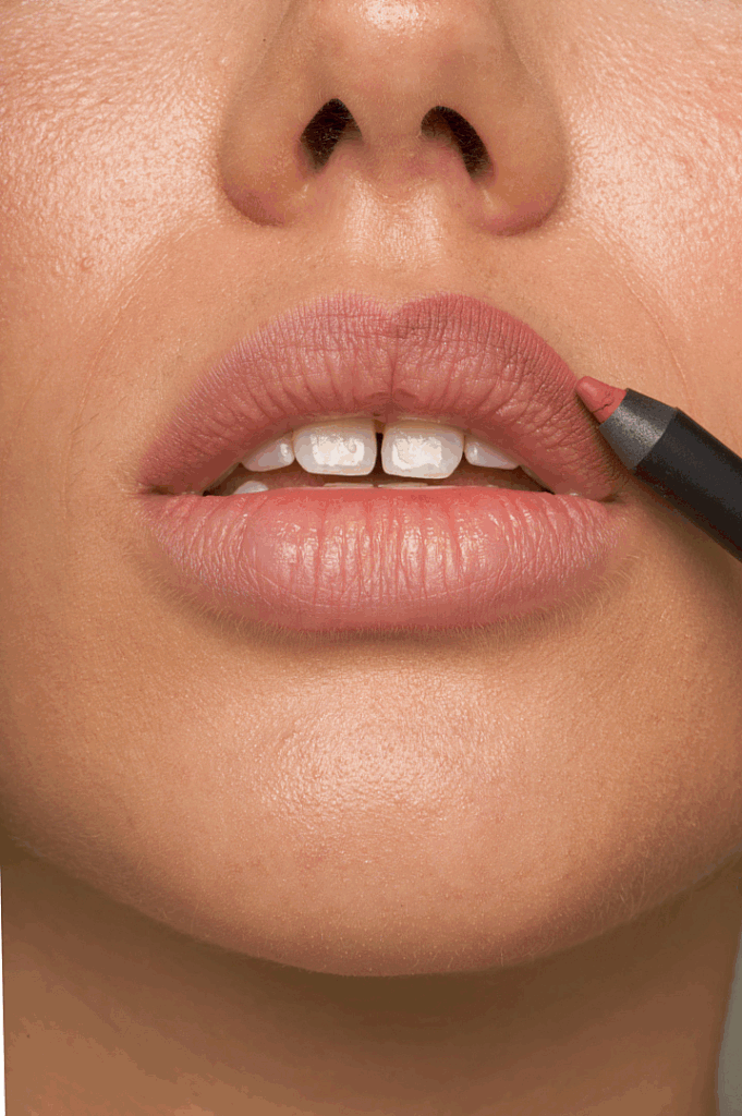 Nahaufnahme von einer Frau, die Lippenstift auf die Lippen aufträgt.