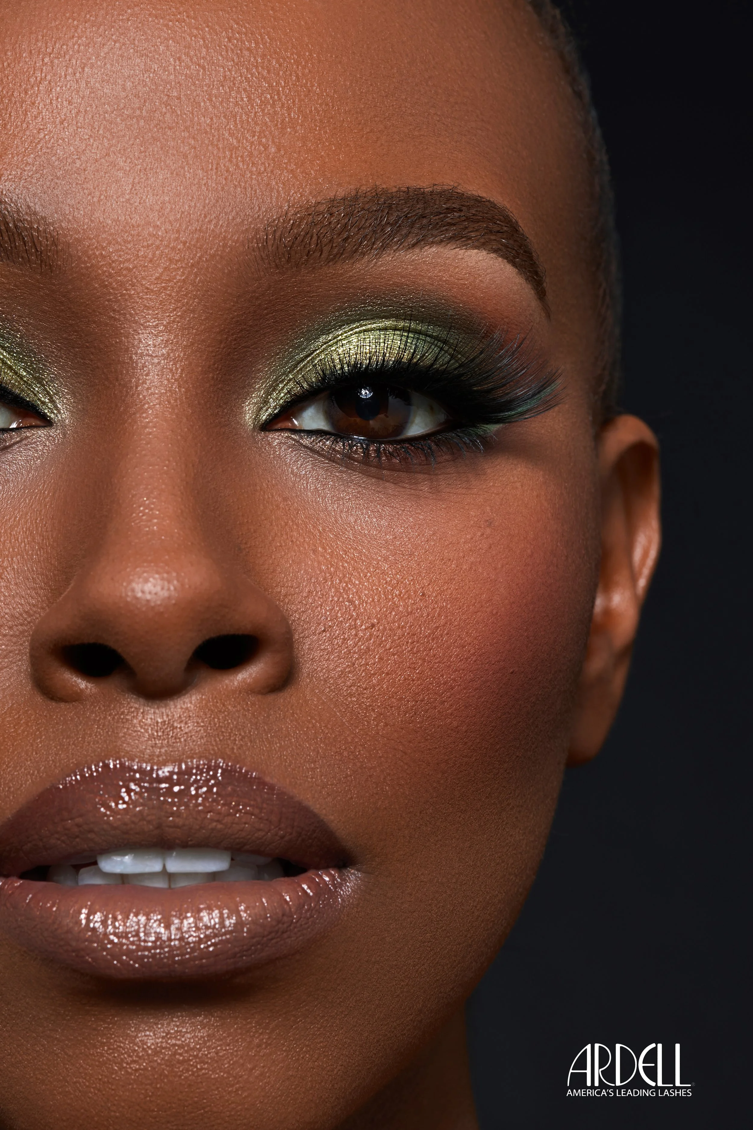 Nahaufnahme eines Models mit grünem Lidschatten, langen Wimpern und glänzenden Lippen, Werbebaum für ARDELL