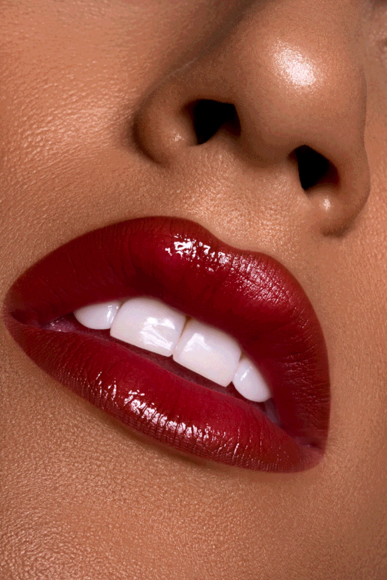 Nahaufnahme von Lippen mit rotem Lippenstift und weißen Zähnen, Gesichtspartie mit Nasenlöchern sichtbar.