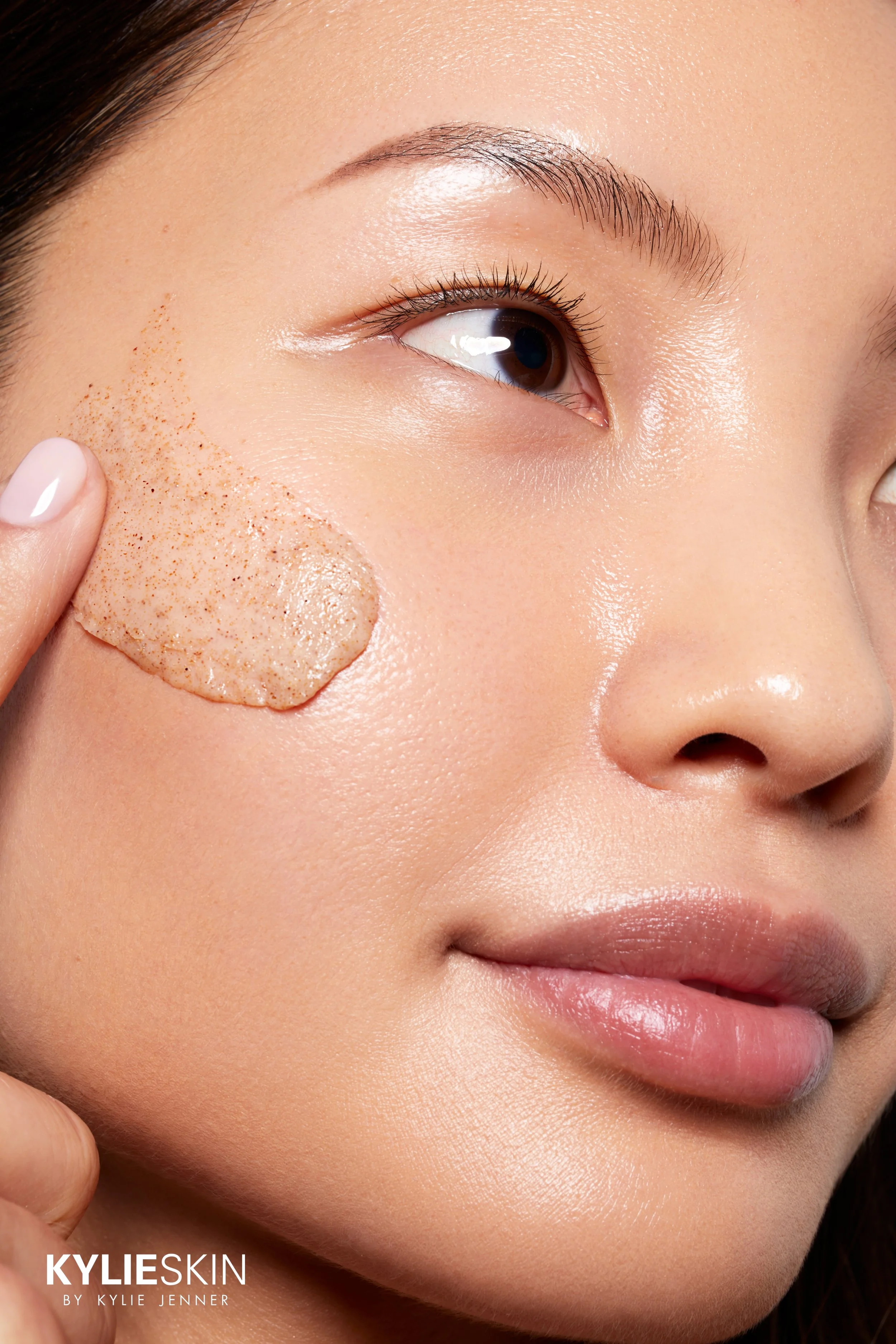 Nahaufnahme einer Frau, die eine Gesichtsmaskenmasse auf ihre Wange aufträgt.