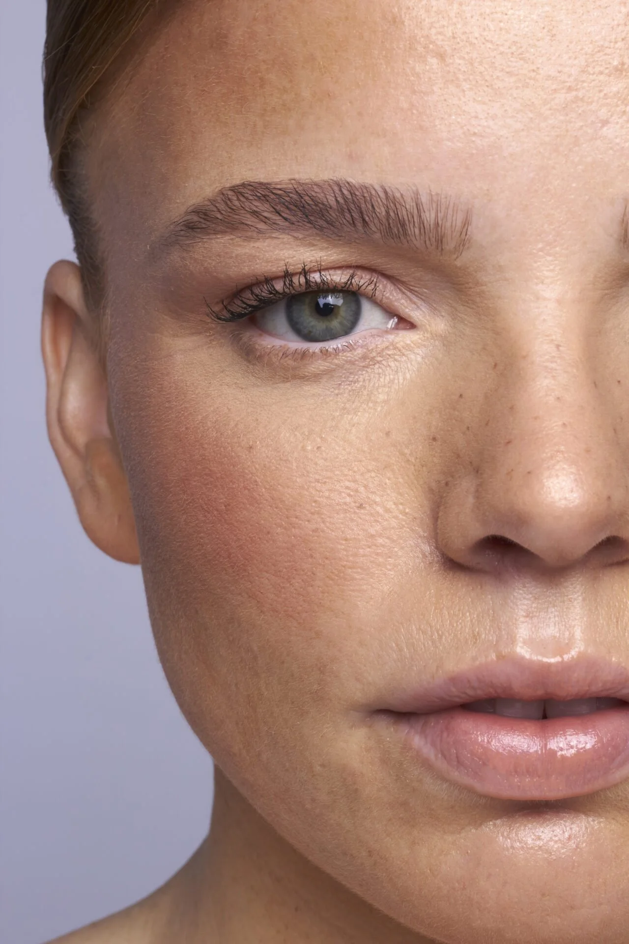 Nahaufnahme des Gesichts einer jungen Frau mit blauer Auge, glatter Haut und gepflegten Brauen.