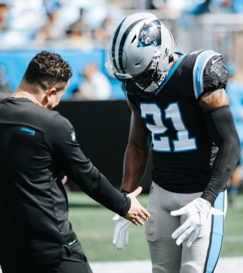 Ale Oliveira, elite athletic trainer and cofounder of Aptare Lab in Indian Land SC, , with Cam Newton on the sidelines of a professional football game, representing elite-level sports performance and athletic training expertise.