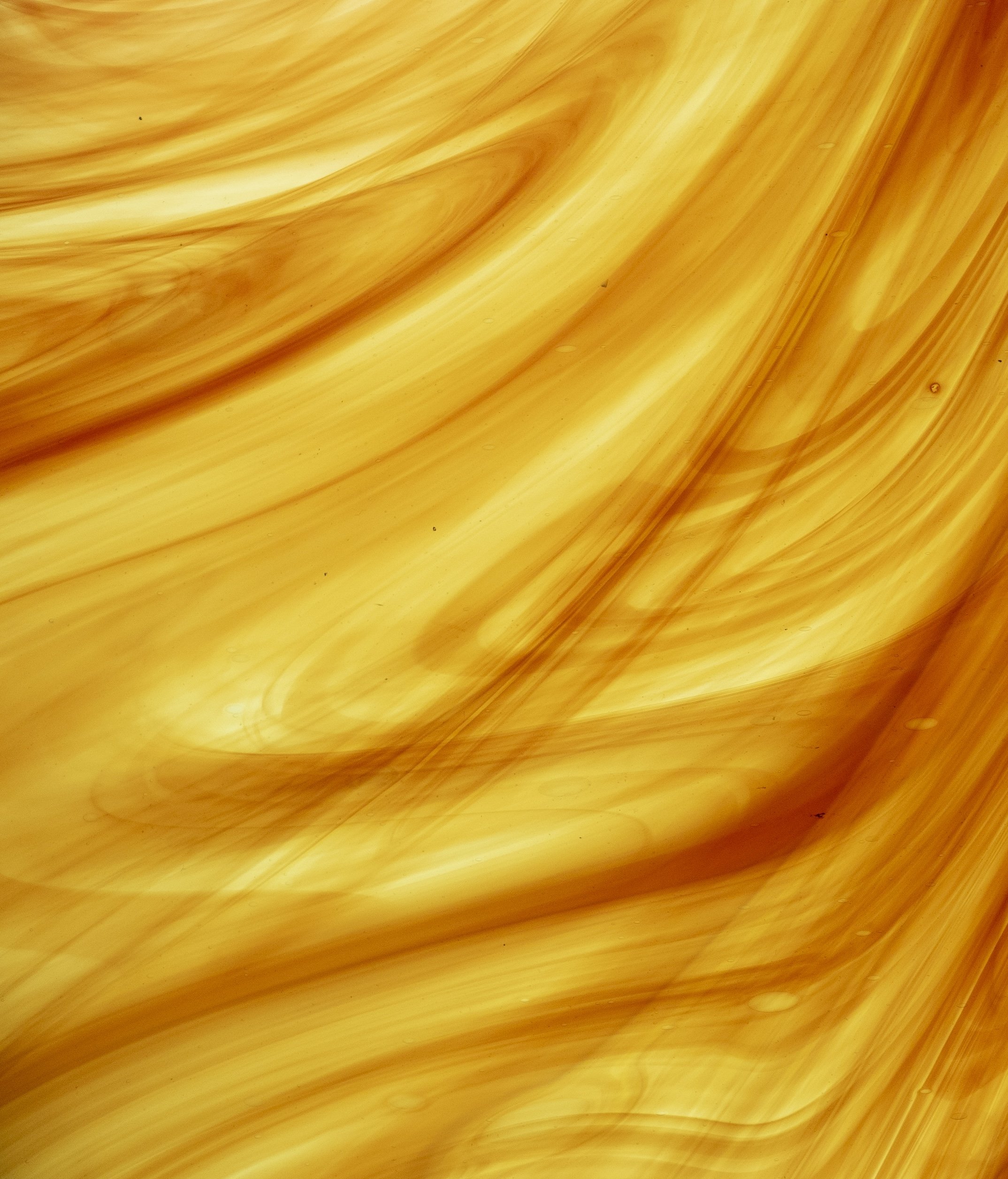 Close-up of a yellow, marbled, abstract pattern with flowing lines and swirls.