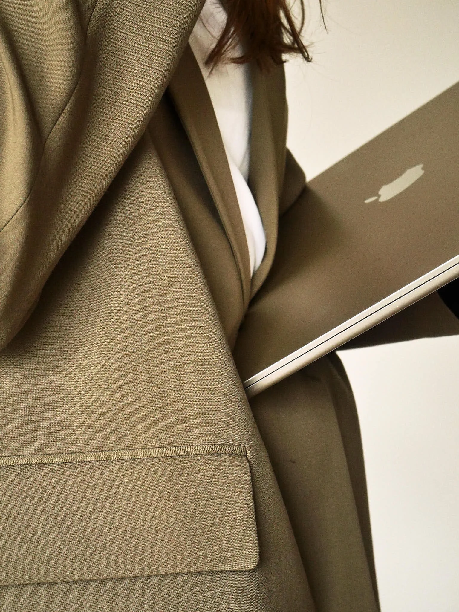 Une personne en costume beige utilise un ordinateur portable Apple sur ses genoux.