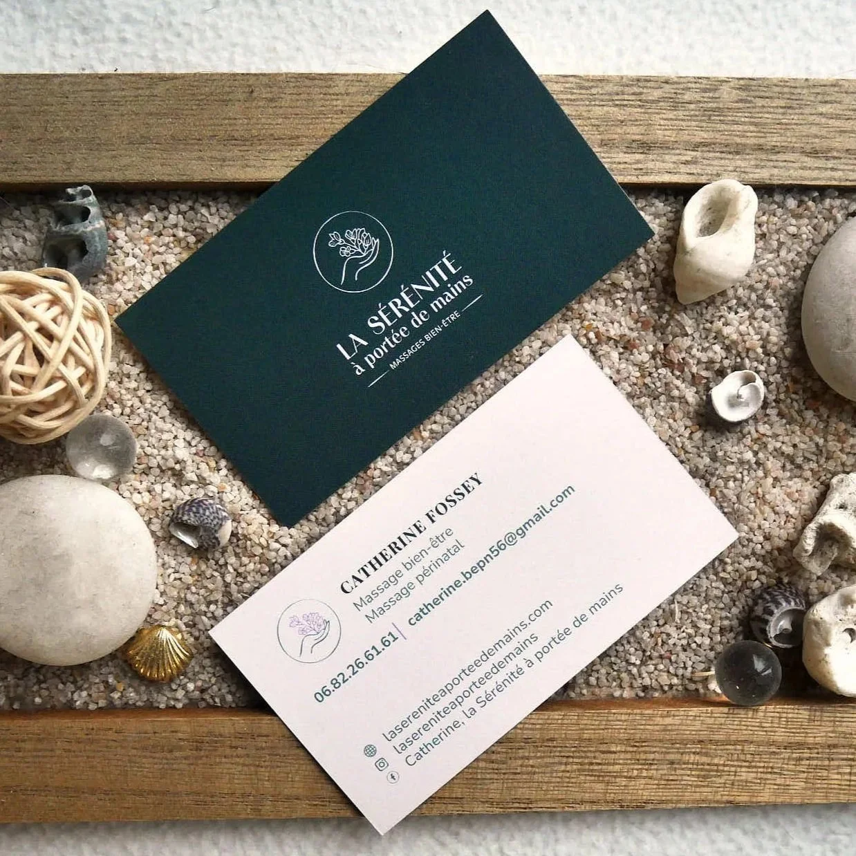 Cartes de visite de praticienne en massages, avec décor de petits cailloux, coquillages, et une boule en rotin.