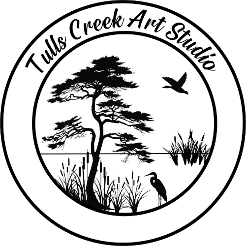 A circular logo featuring a pine tree, grass, and a bird in flight with the text 'The Creek And Shadows' around the top.