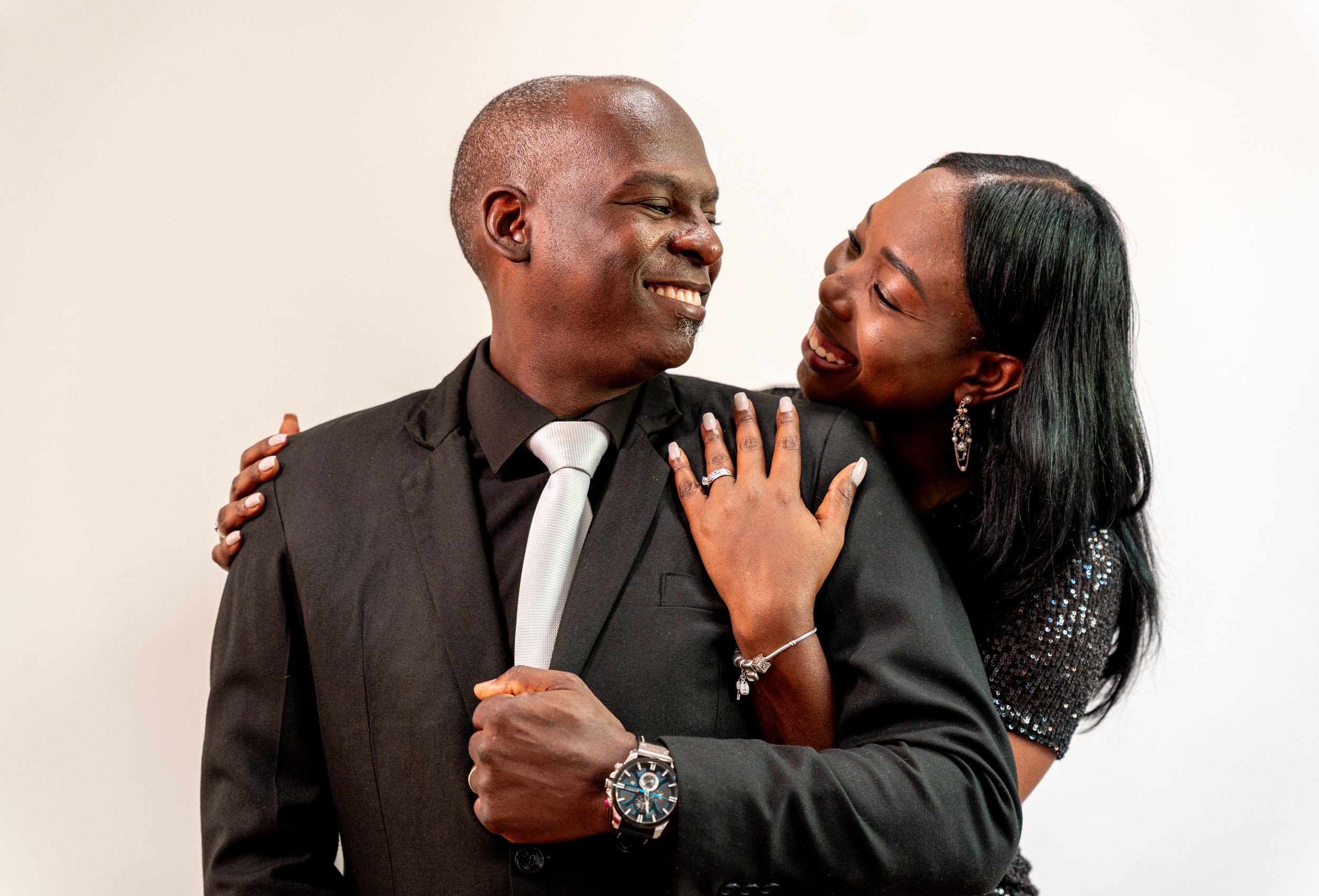 Una pareja feliz en un abrazo, hombre con traje y mujer con vestido brillante, ambos sonrientes.