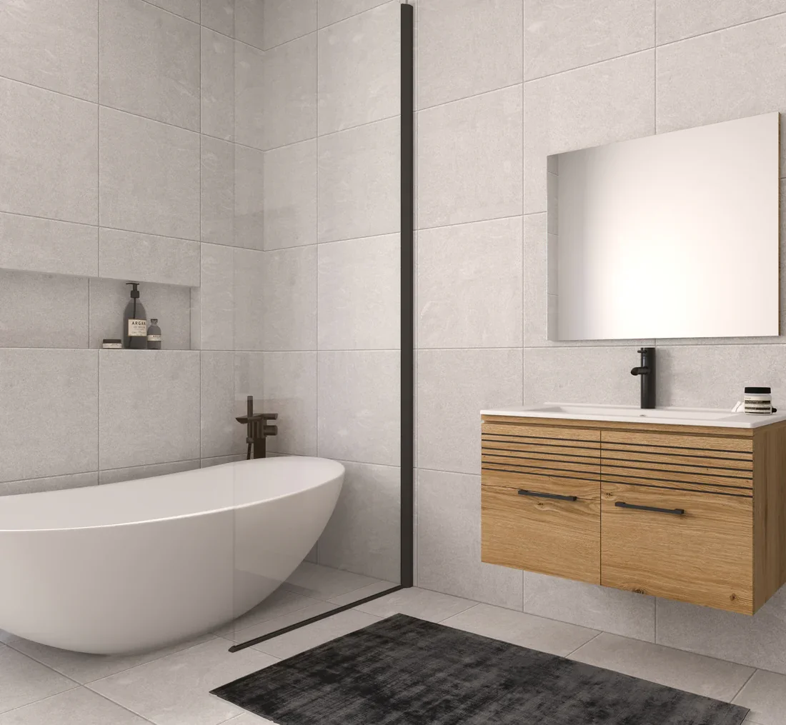 Modern bathroom with a freestanding bathtub, a wooden vanity with a mirror, and a black and gray bath mat on light gray tiled floor and walls.