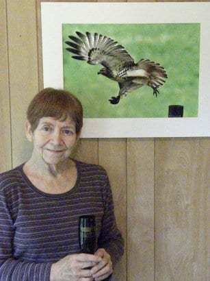 Nema Andahadna sonriendo frente a un cuadro de un halcón en vuelo.