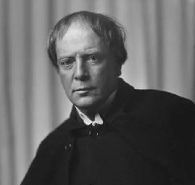 Retrato en blanco y negro de Arthur Machen con cabello rubio y expresión seria, vestido con una túnica negra.