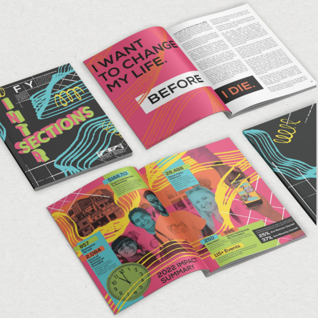 Colorful magazine opened to a two-page spread with a vibrant design, a group photo, and sections of text. Other magazines with similar bright, abstract covers are nearby.