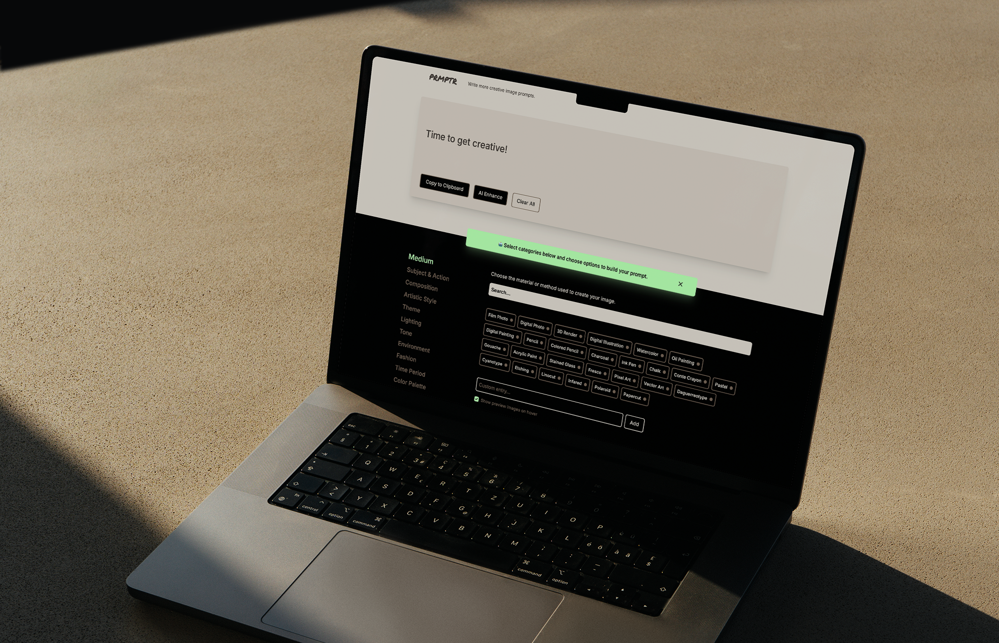 Open laptop on a beige surface displaying an online art prompt generator website with a prompt saying 'Time to get creative!'