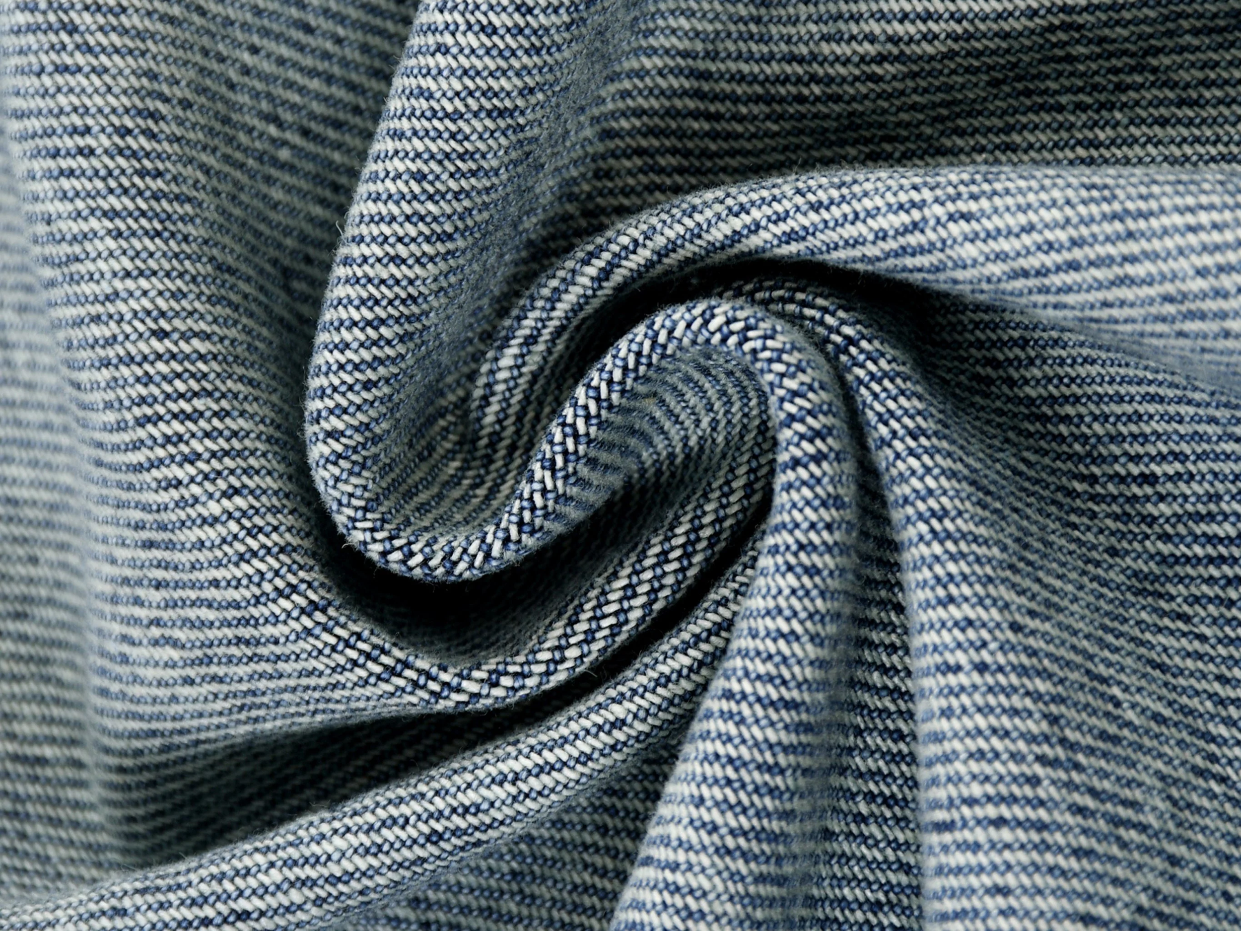 Close-up of blue denim fabric with a twisted center, showing textured weave pattern.