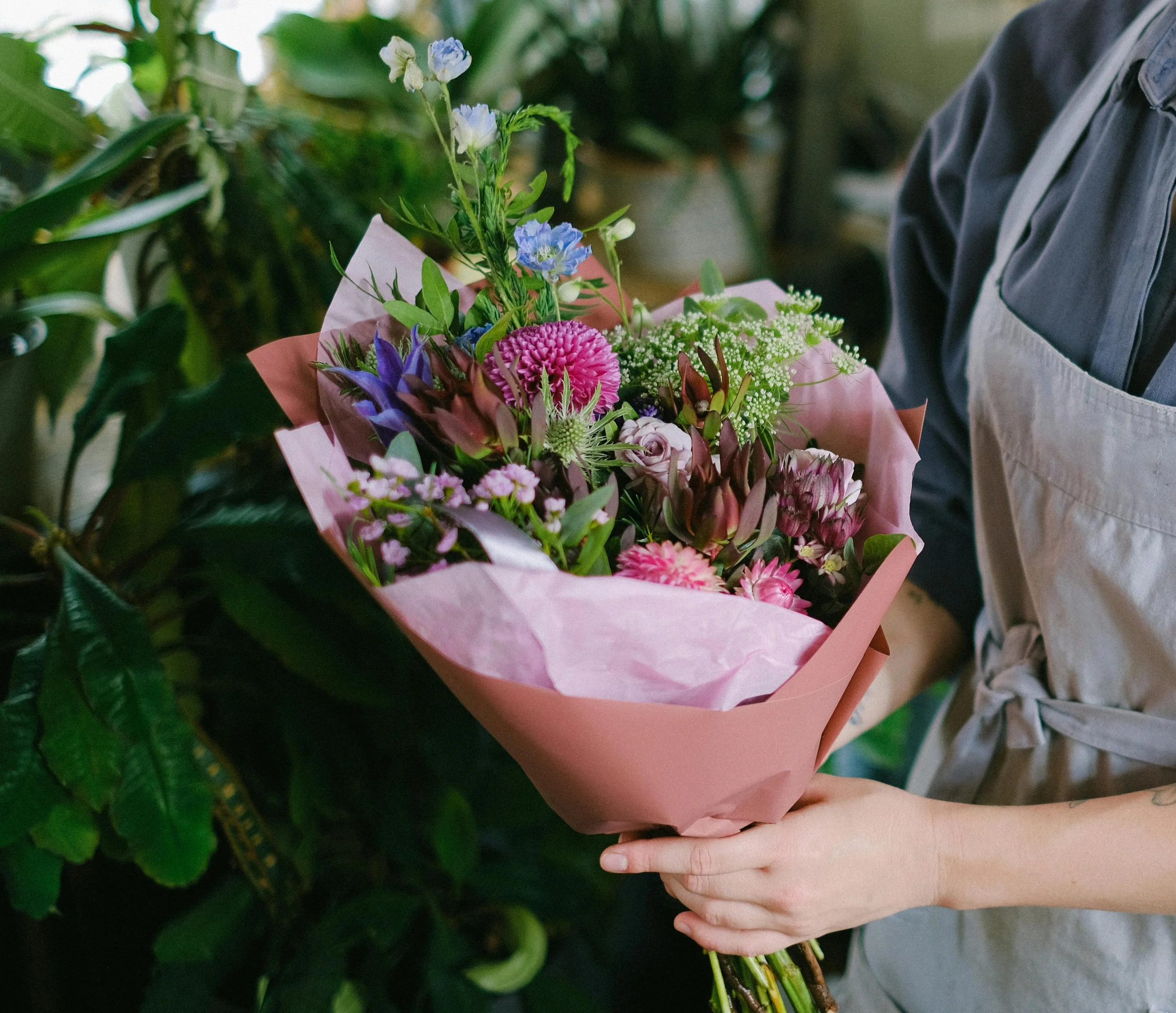 Seasonal arrange-at-home bouquet wrapped in kraft paper, held by hands, feathuring fresh flowers from Poetry in Flowers in Hednesford.