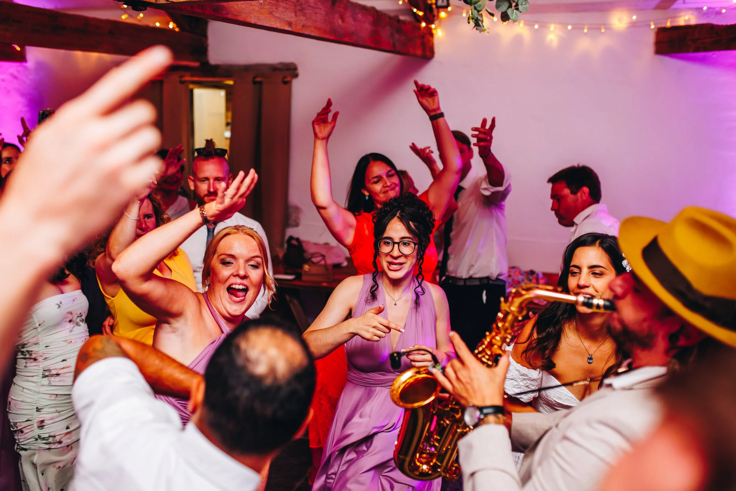 Wedding dance floor packed with guests celebrating while a sax player performs live during the couple’s first dance set.