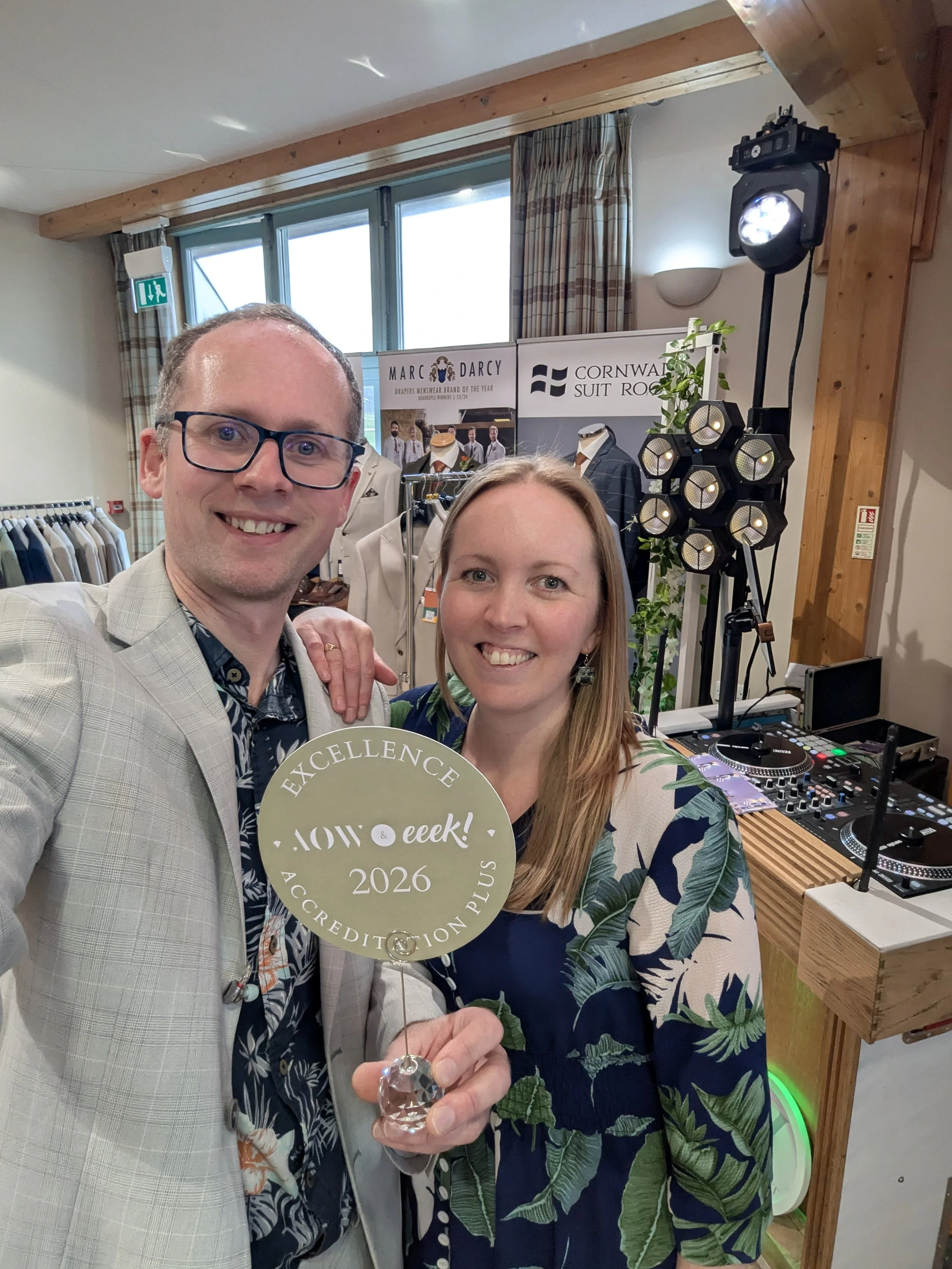  John and Amanda smiling at a selfie at an event, holding an award plaque that reads 'Excellence, AOW & EEK! 2026, Accreditation Plus'.