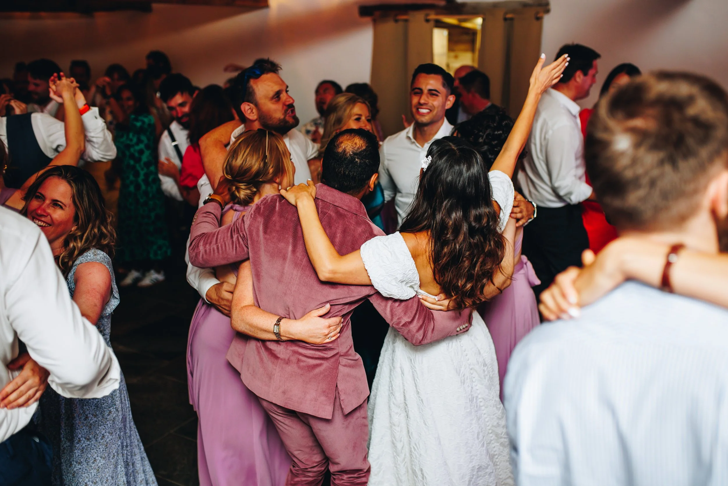 Bride and Groom dancing with guests and celebrating at a wedding reception, with smiles and lively expressions. At Wonwood Barton