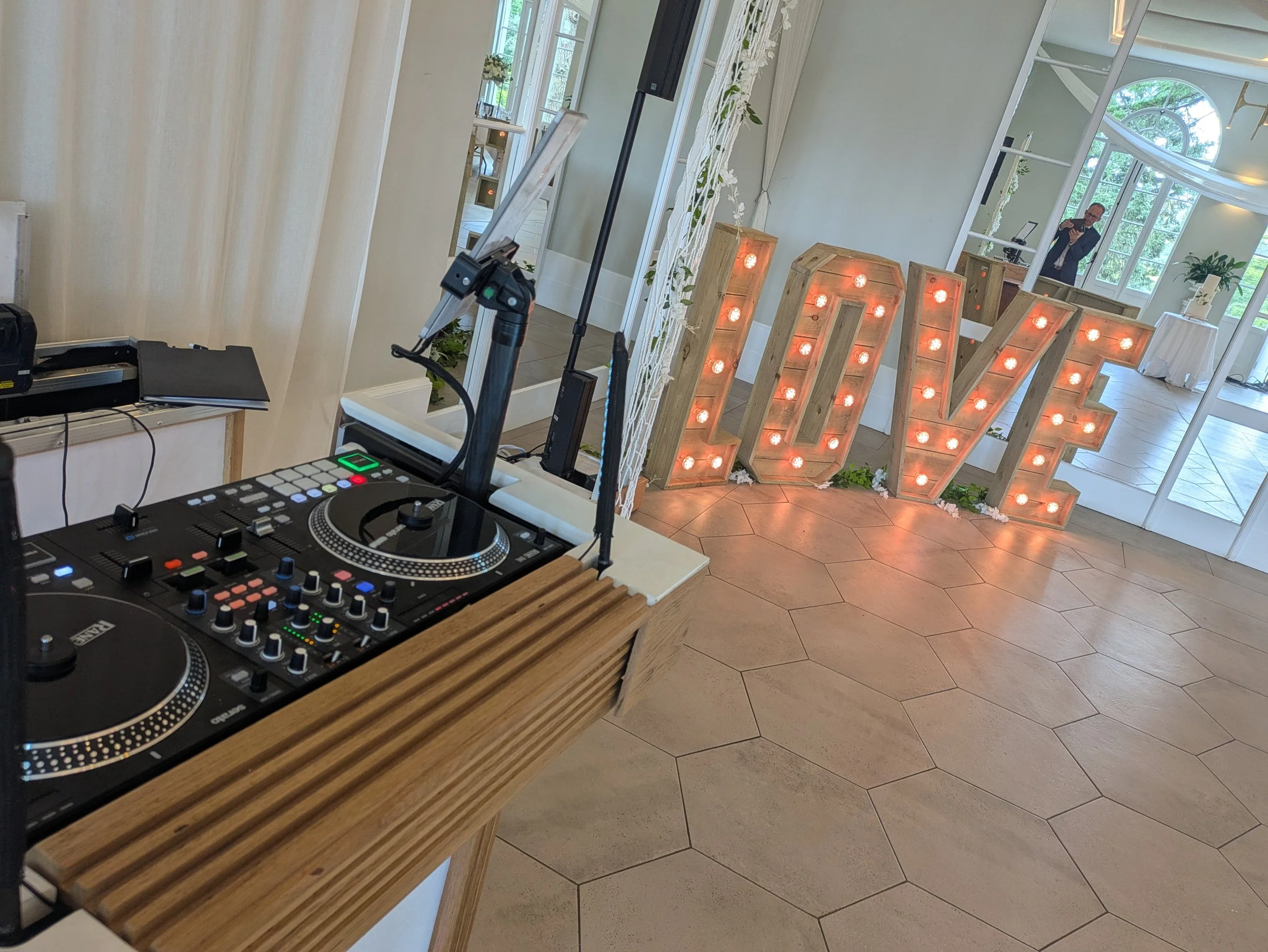 Rustic wedding DJ setup at Deer Park featuring oak DJ furniture, professional DJ decks, floral styling and illuminated LOVE letters.