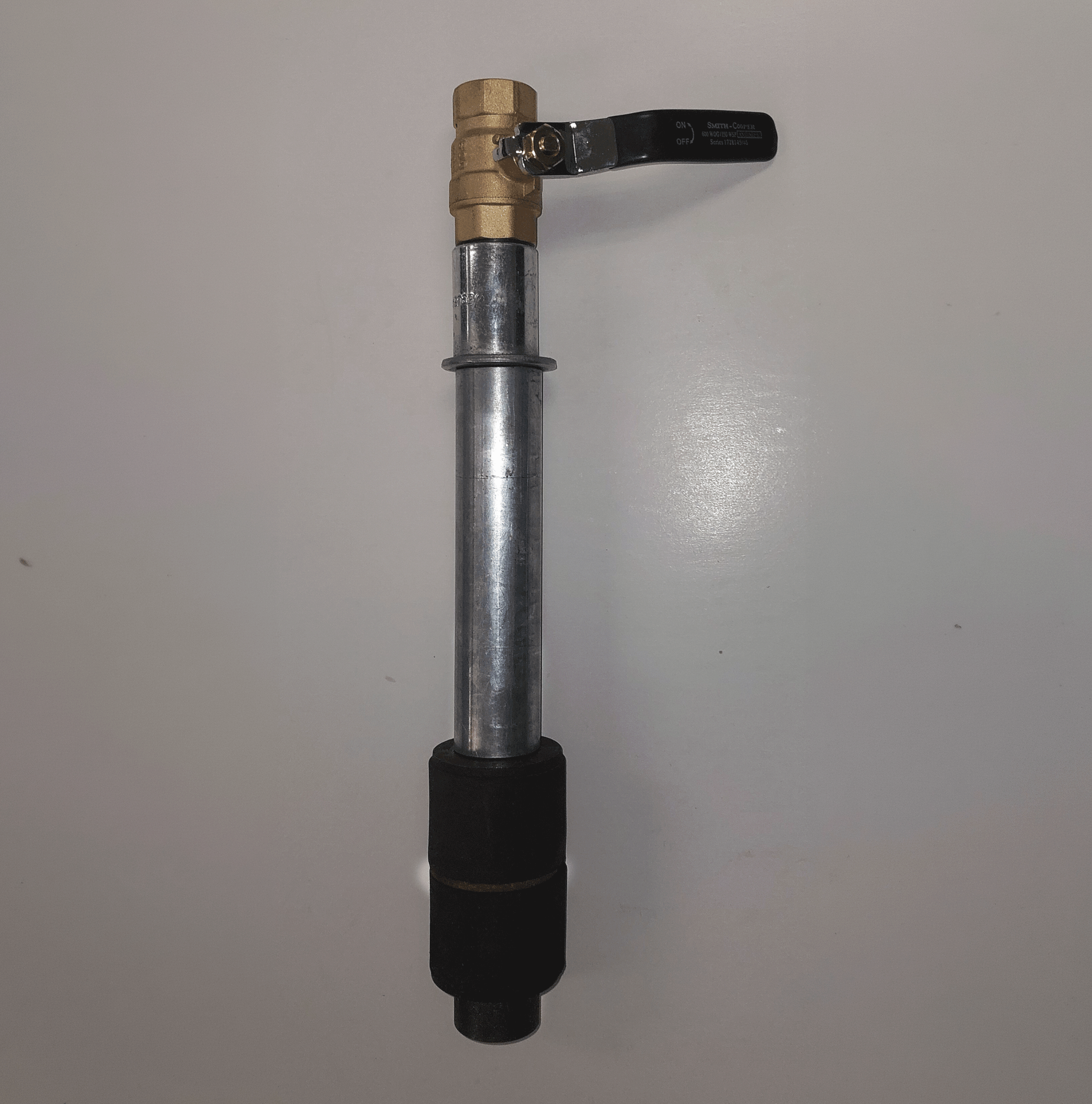 A grout packer with a brass valve and a black handle on a plain white surface.