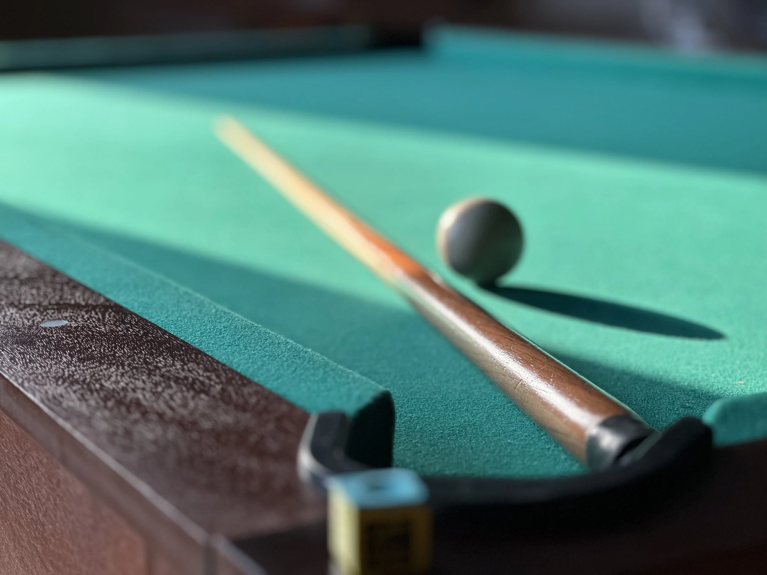 Taco de billar con bola en una mesa de billar verde y un taco de billar en posición