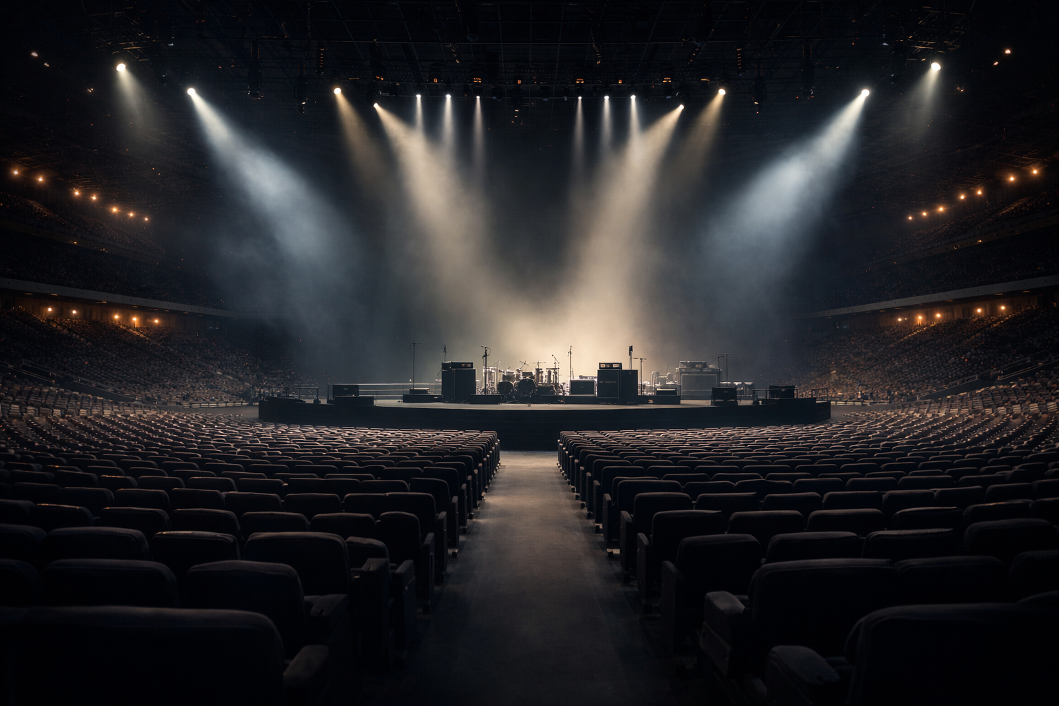Empty concert arena with a stage set up for a live music performance, featuring musical instruments and amplifiers, illuminated by bright spotlights with smoke effects.