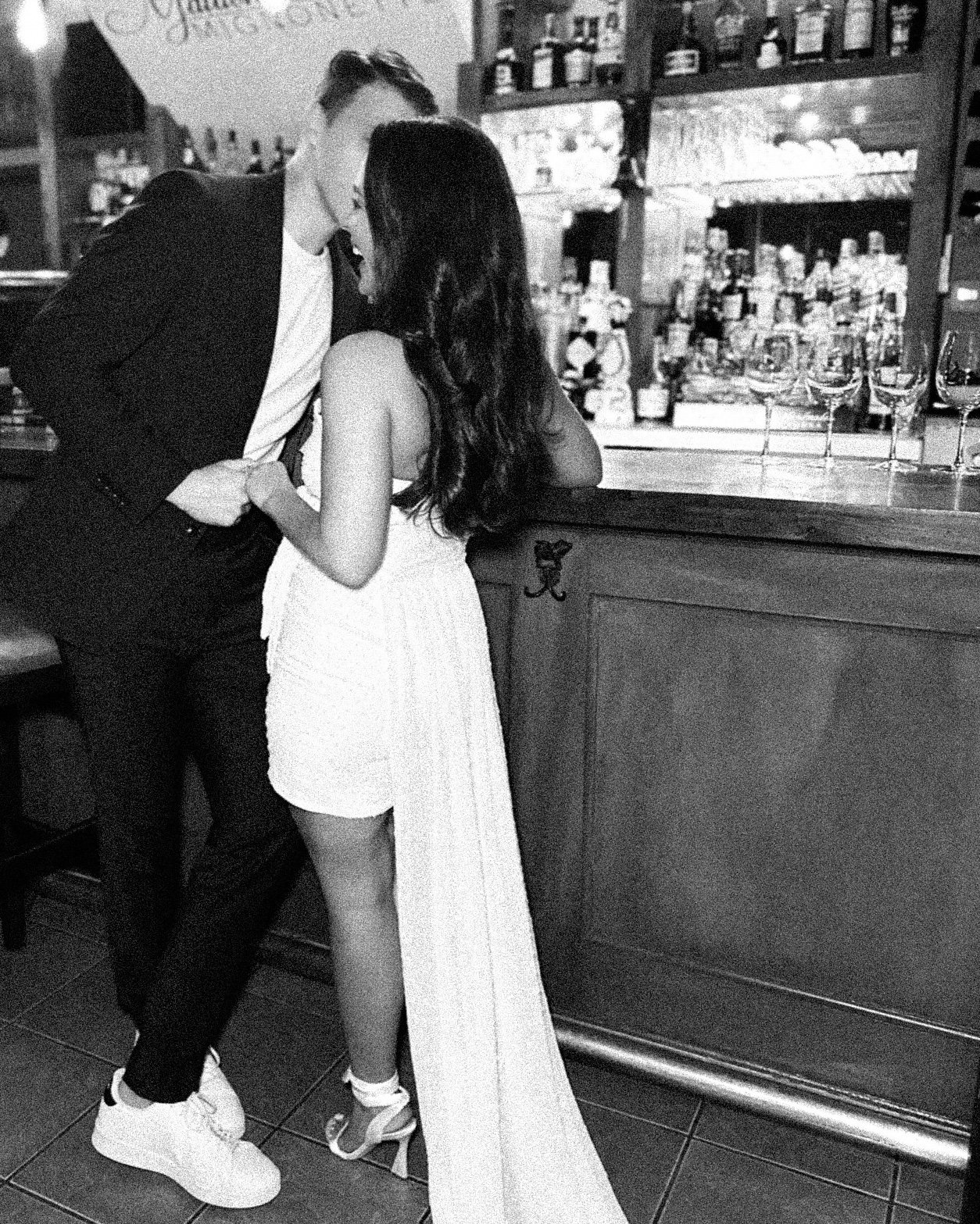 Rehearsal dinner bride and groom cozying up at the bar as their content creator captures this intimate moment