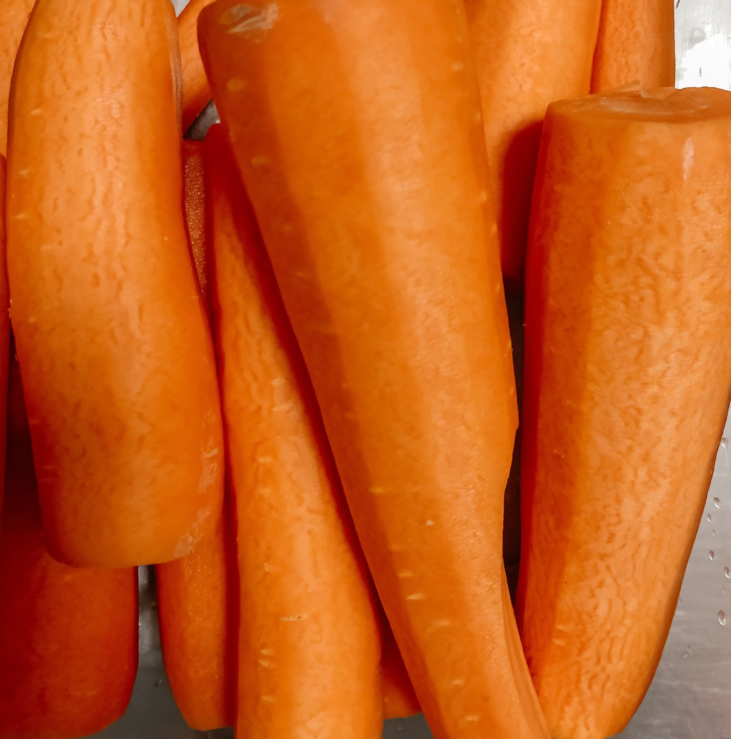 Close-up of several peeled carrots on a metallic surface.