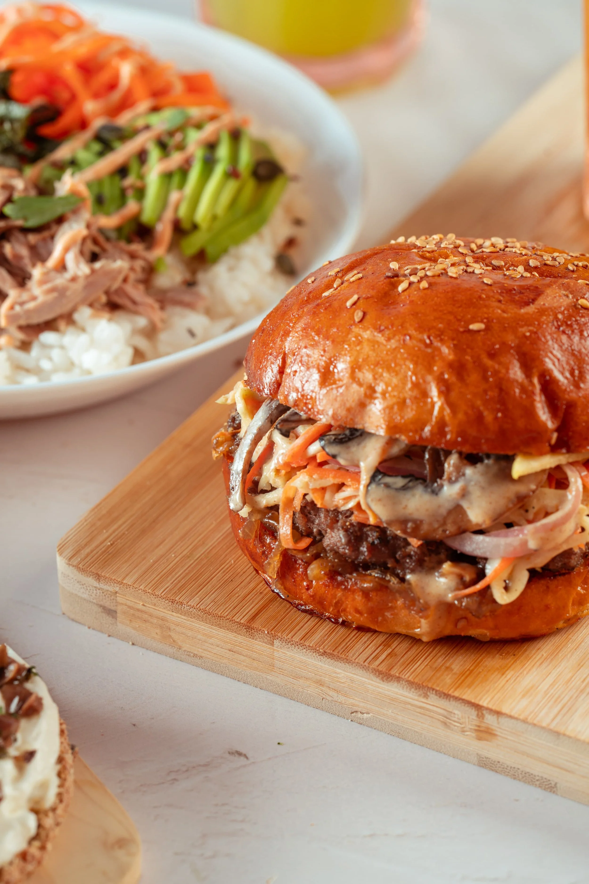 A pulled pork sandwich with coleslaw on a toasted bun, served on a wooden board.