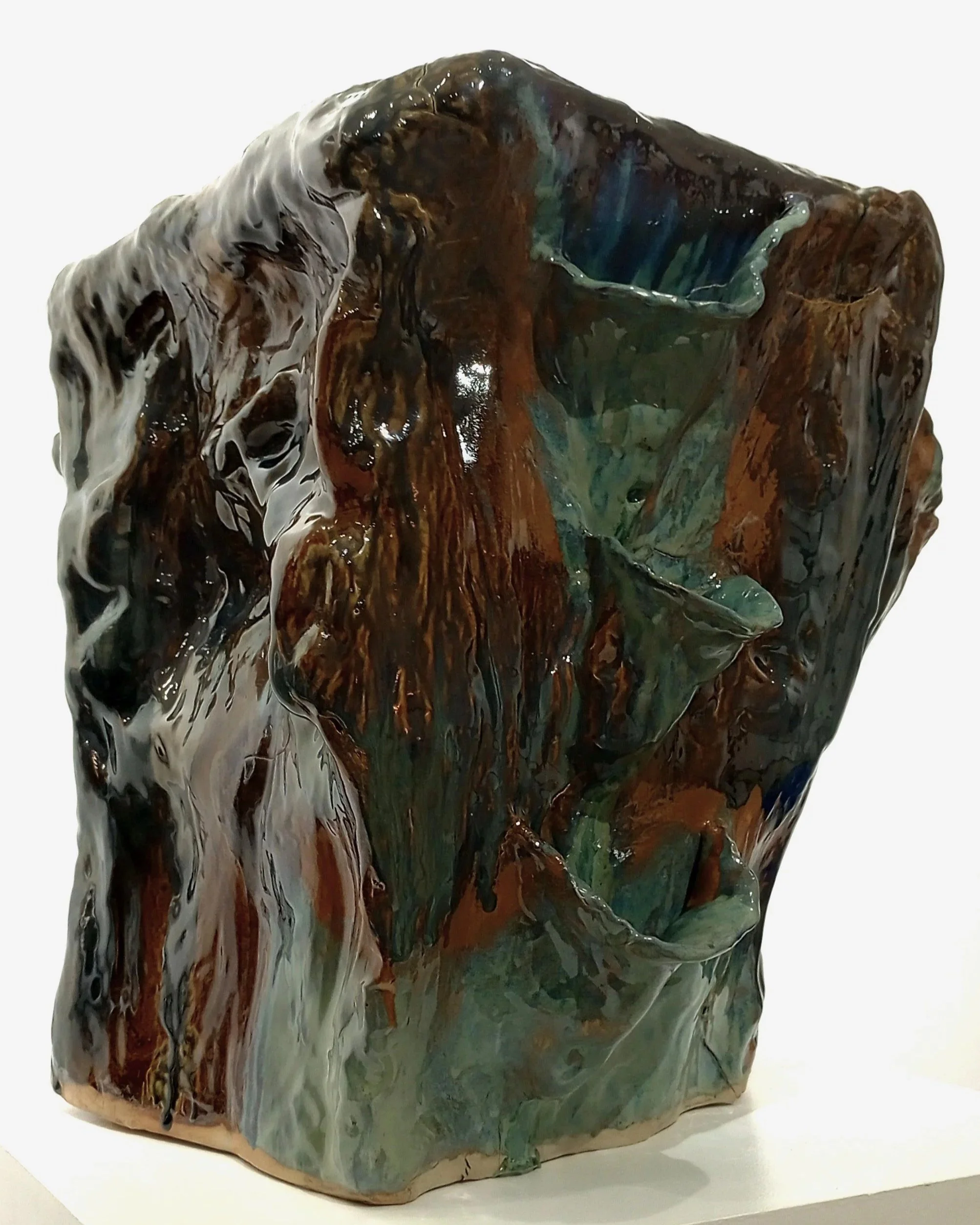 Large brown, black, gray, green, and blue ceramic sculpture with side pockets for plants.