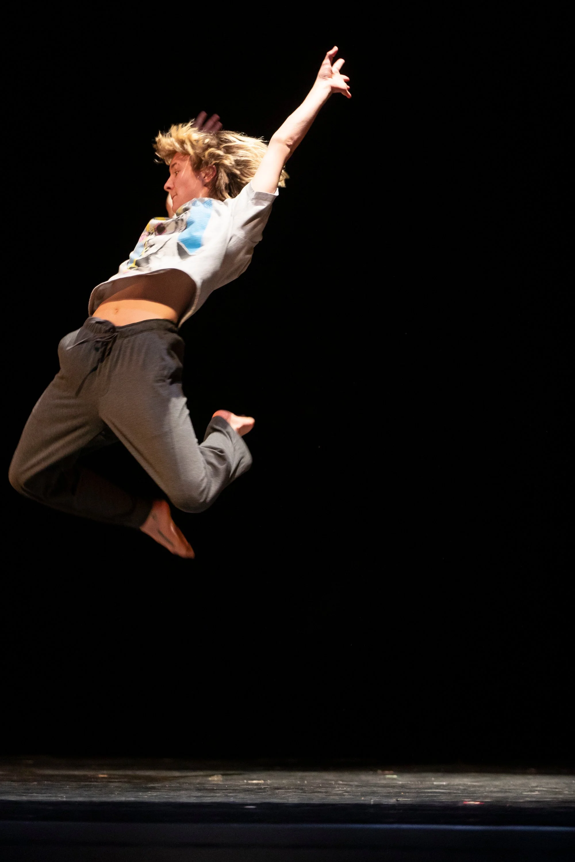 ZEWJ jumping with both legs bent and arms up.