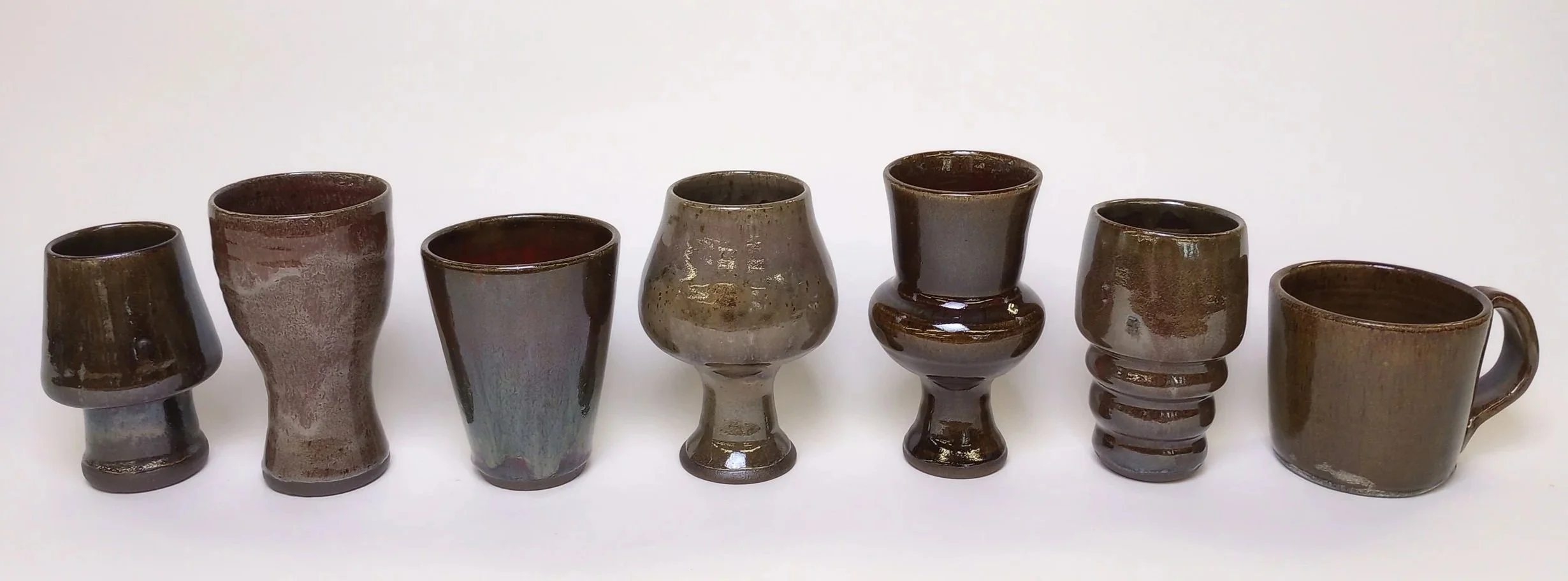 Row of seven different shapes of ceramic cups