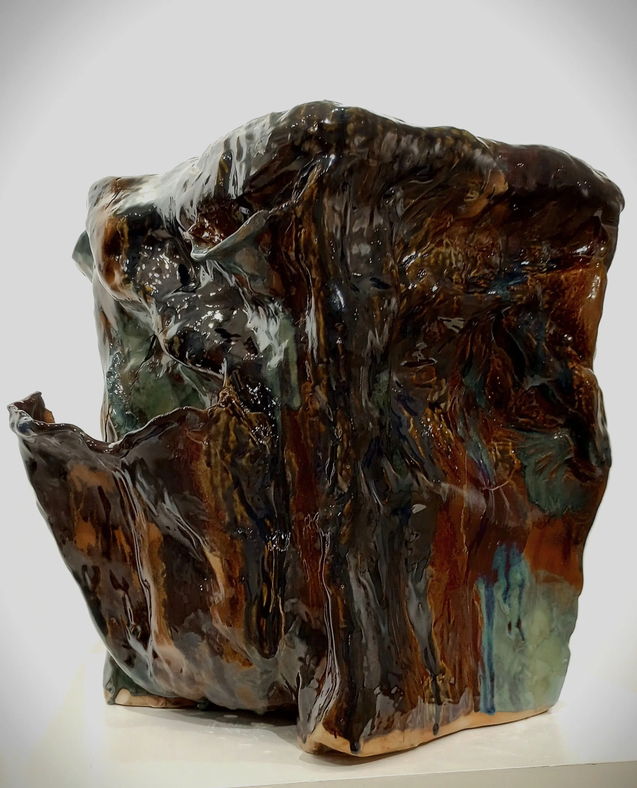 Large brown, black, dark orange, and blue ceramic sculpture with side pockets for plants.