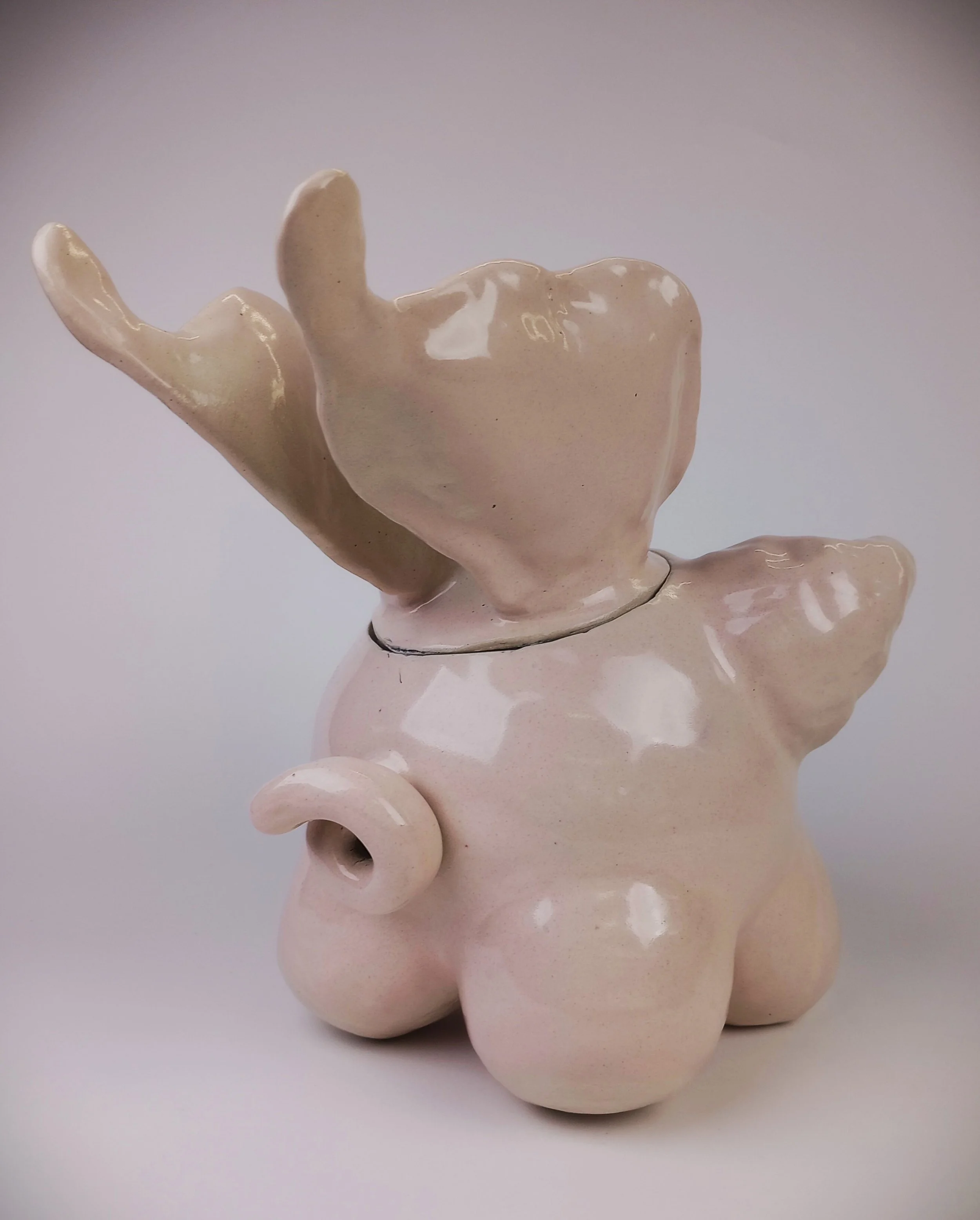 Back of a light pink pig sculpture with curly tail and wings.