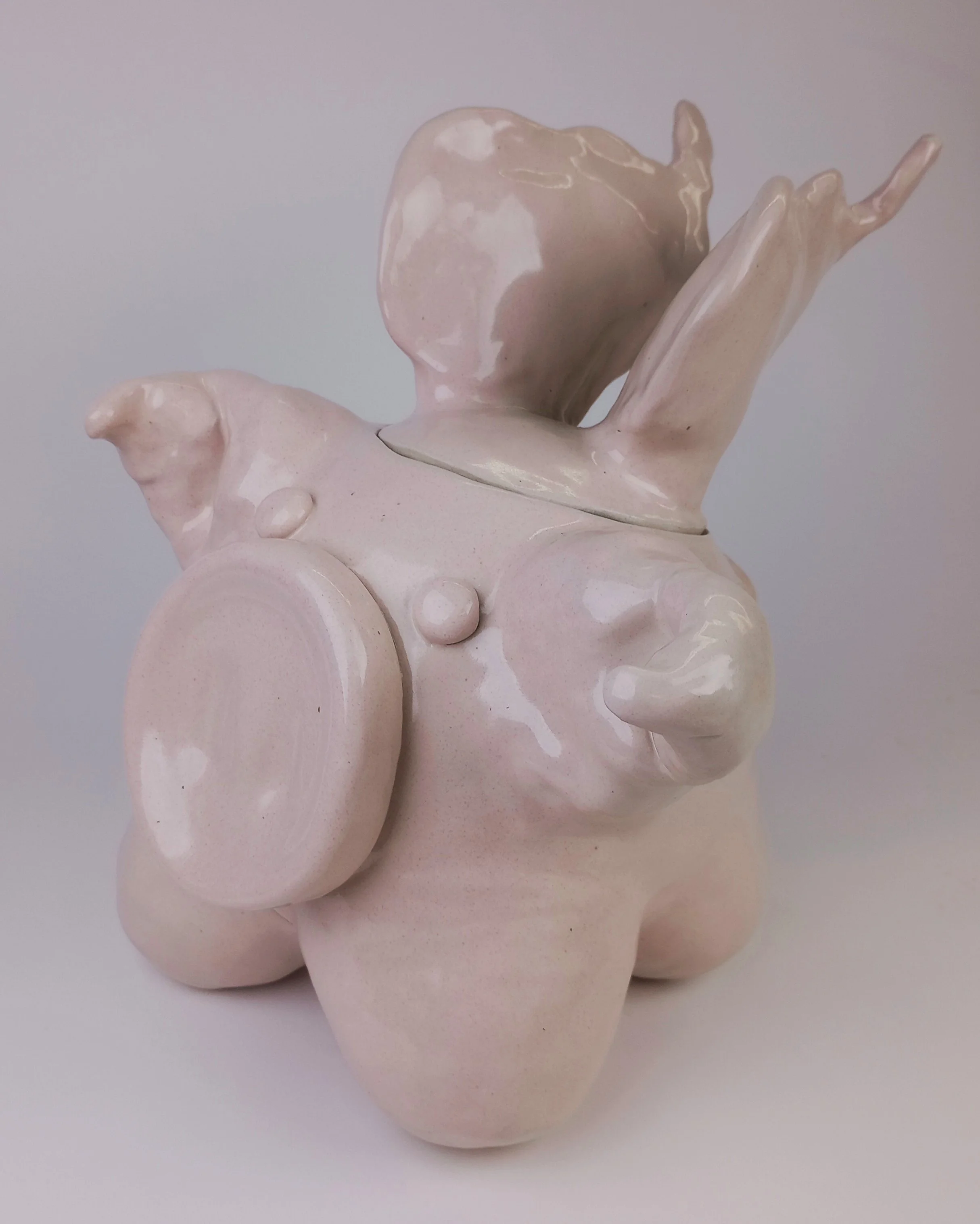 Light pink pig sculpture with wings and a big nose.