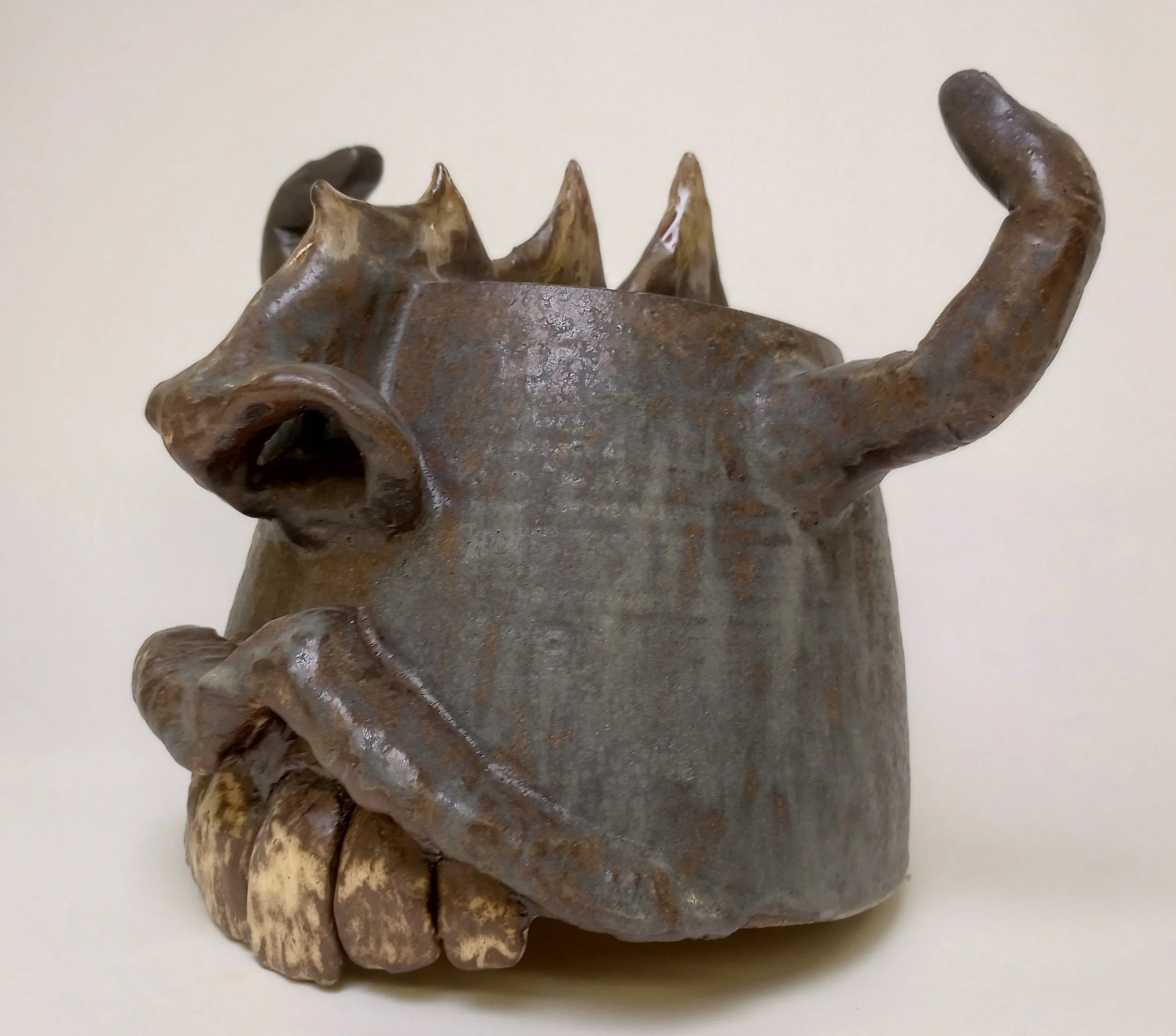 Side view of ceramic helmet with big teeth, finger horns, and spikes.