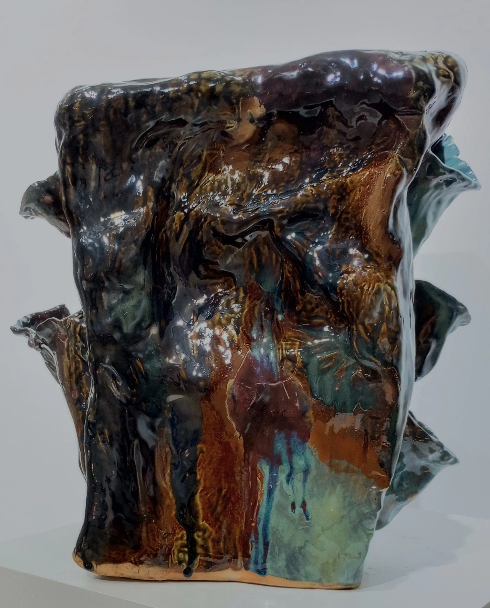 Large brown, black, green, and blue ceramic sculpture with three pockets on one side and two pockets on the opposite side.