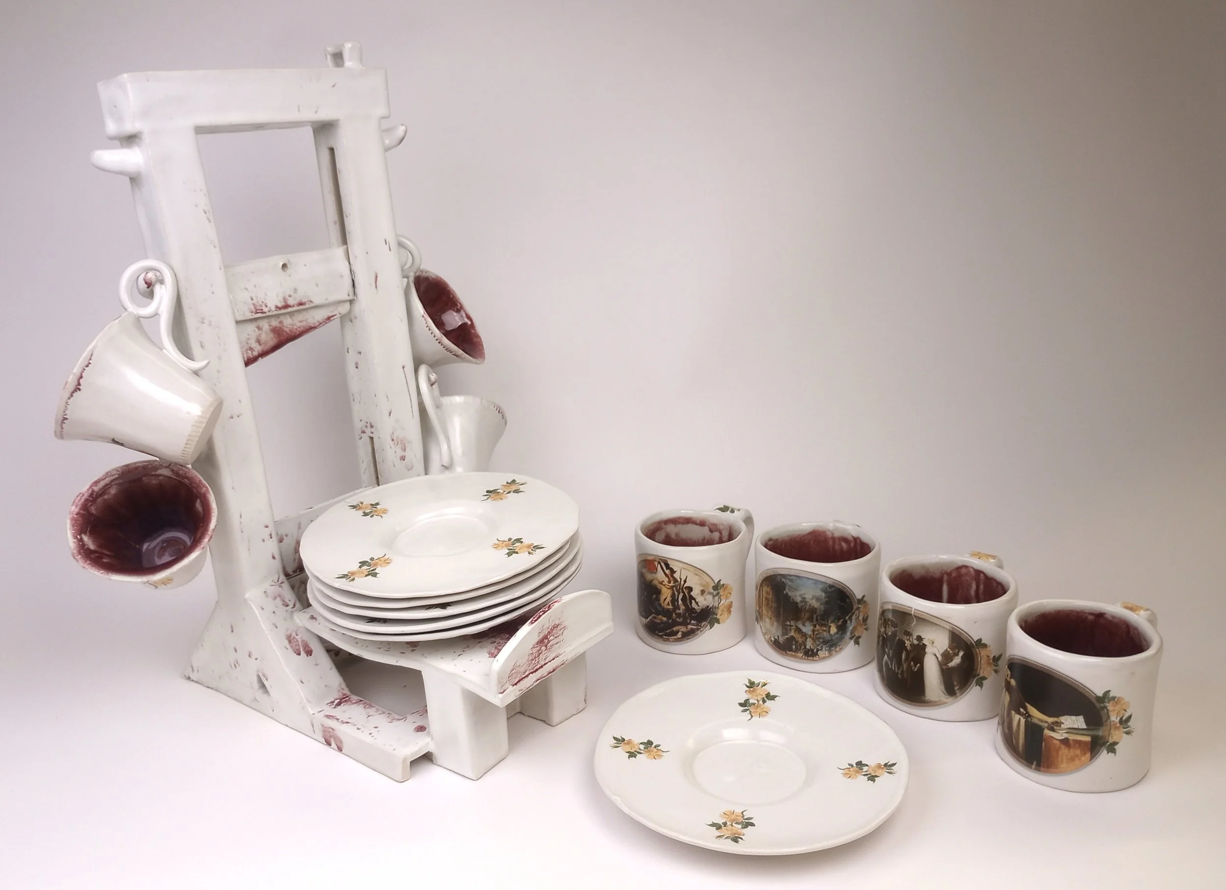 Ceramic tea set with four coffee mugs, four teacups, and six plates stacked on a guillotine serving stand.