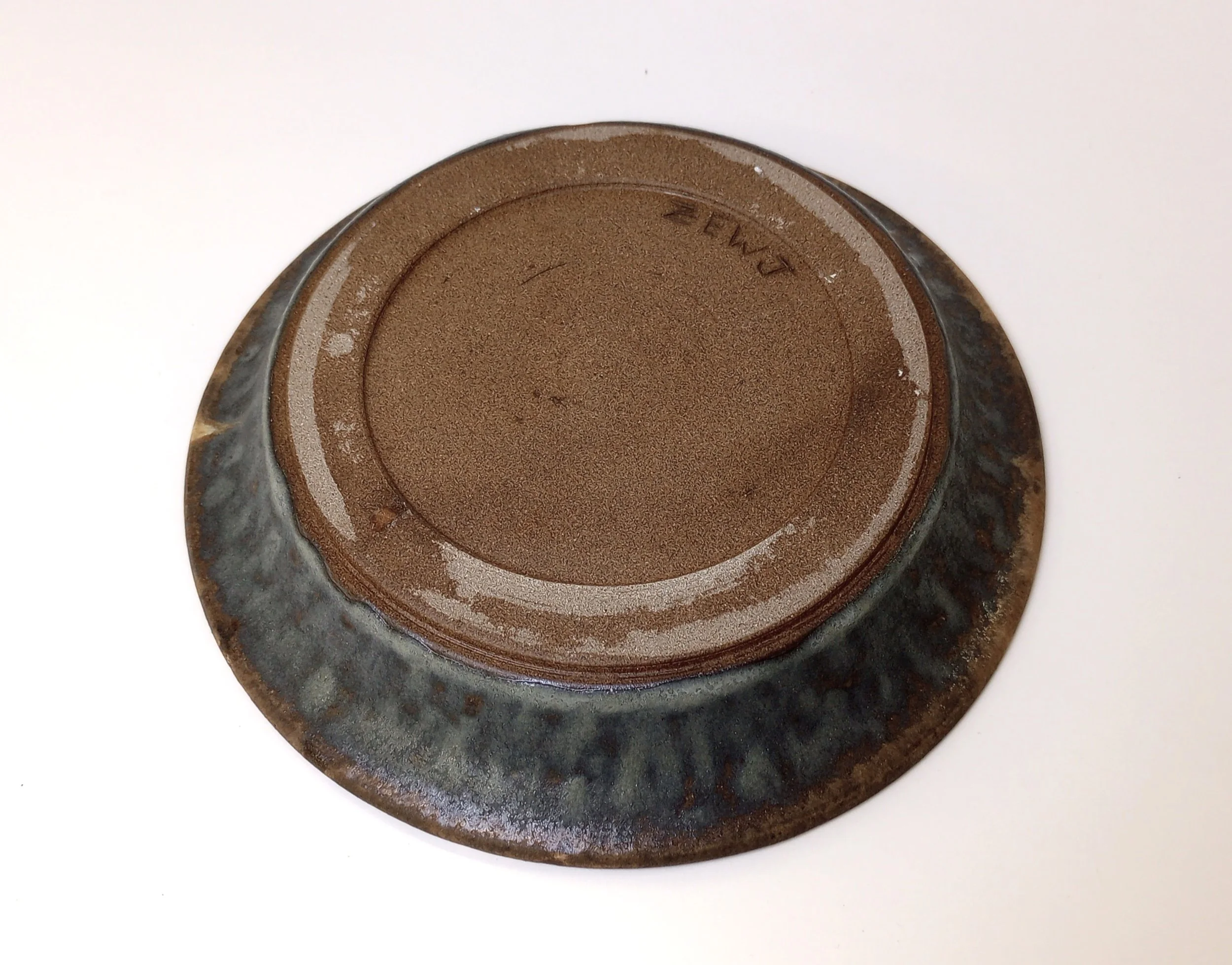 Bottom of a gray and brown ceramic plate inscribed with "ZEWJ."