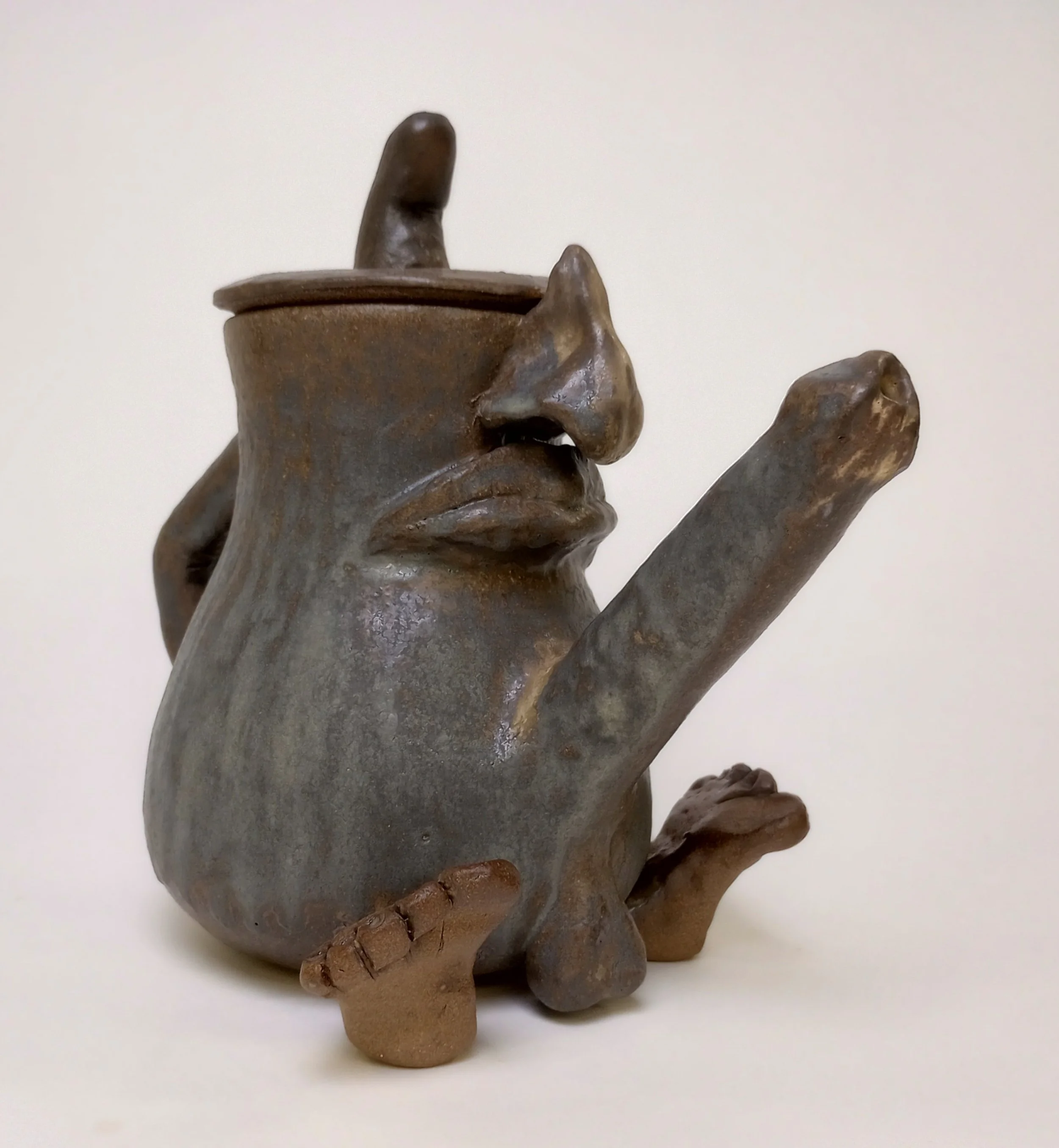 Ceramic coffee pot with a face, feet, and penis spout. 