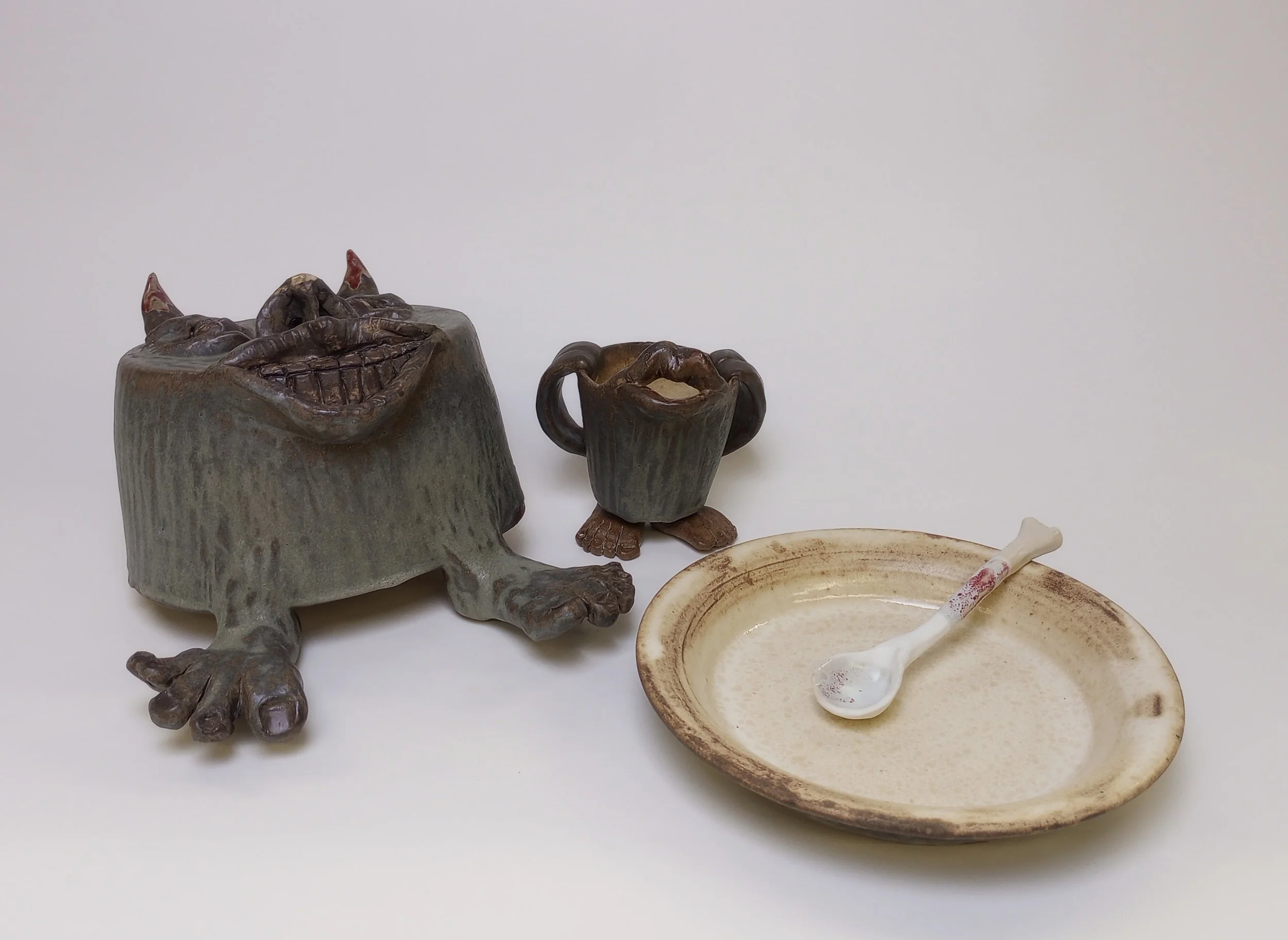 Helmet with feet sitting beside a mug and a plate with a spoon.