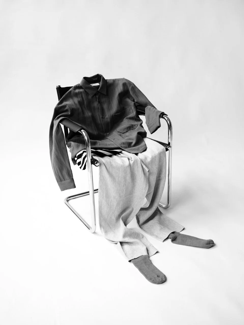 Black leather shirt and light-colored pants draped over a wheelchair in a monochrome photo.