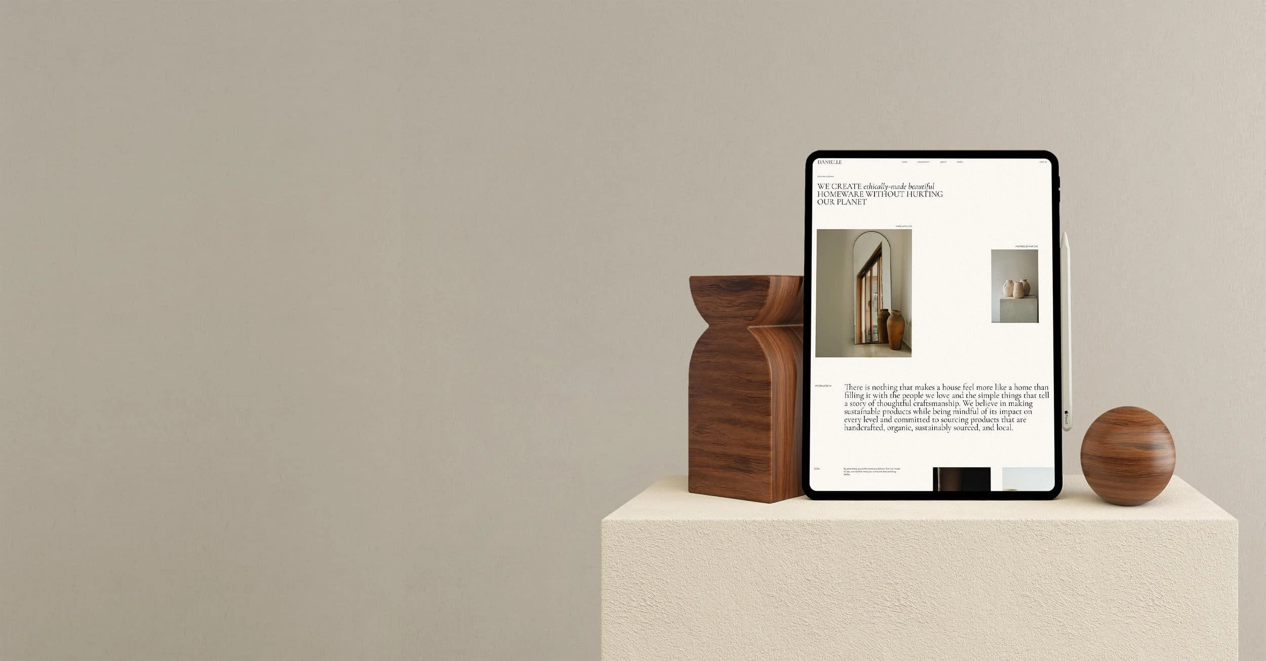 Verso Visual - Premium E-commerce Template - A tablet displaying a website with images of home decor, placed on a beige textured pedestal, with a wooden vase and a round wooden sculpture beside it, against a neutral background.