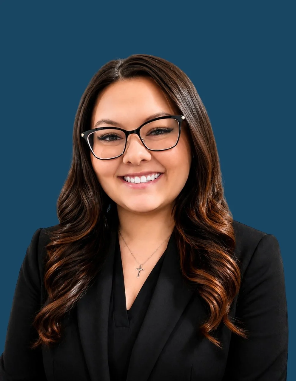 Portrait of Libbey Fall, Business Office Manager/Human Resources, smiling while wearing black-framed glasses, a black blazer, and a silver cross necklace against a dark blue circular background.