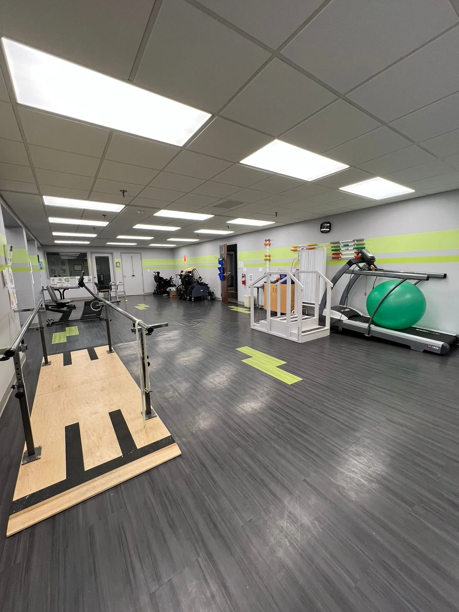 Empty physical therapy or rehabilitation gym with balance boards, treadmills, exercise balls, and therapy equipment.