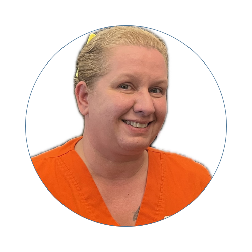 A woman with blonde hair tied back, wearing an orange medical uniform, smiling at the camera.