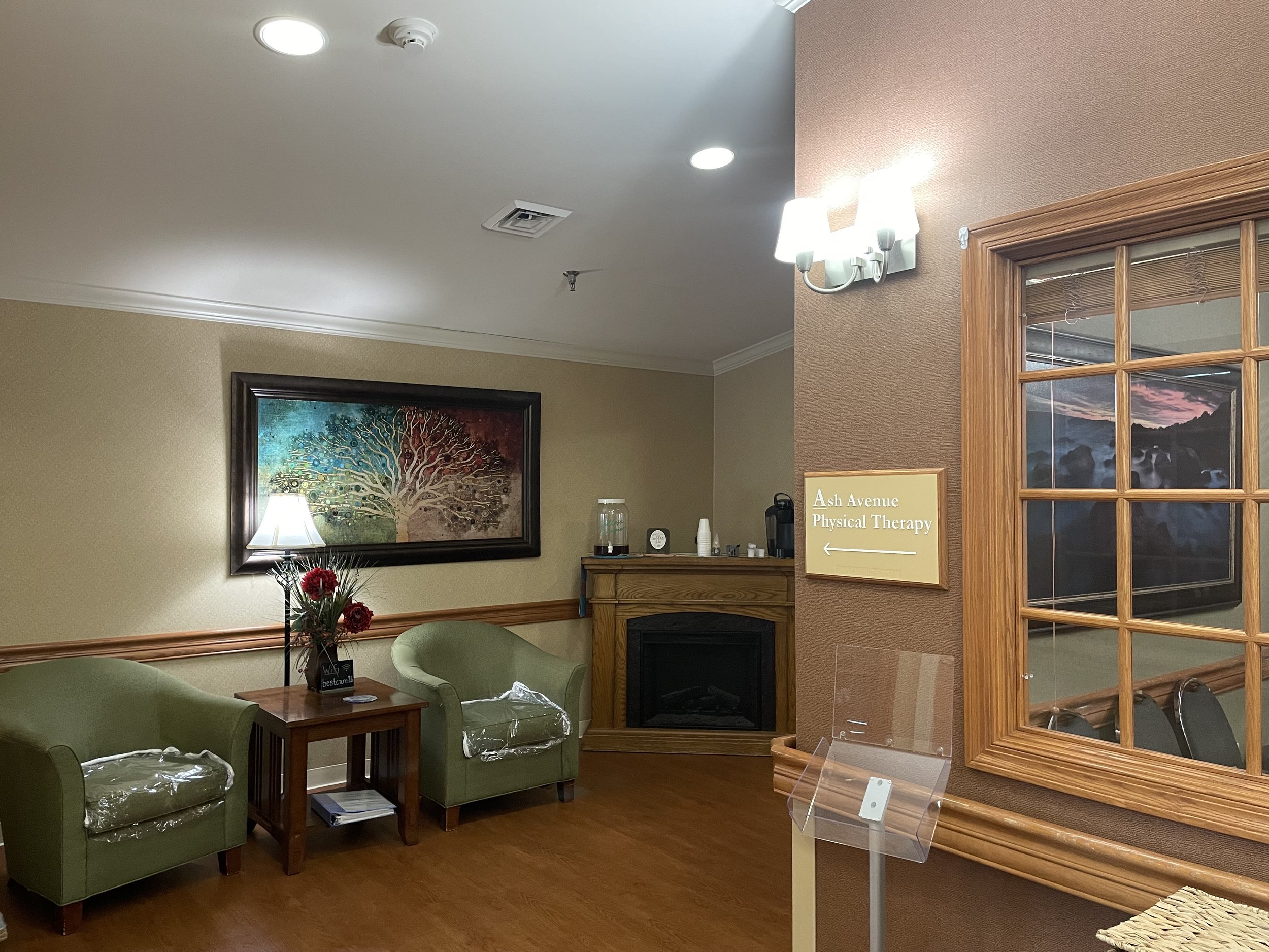 Welcoming lobby lounge at Fieldstone Nursing and Rehabilitation Center with cozy fireplace and Ash Avenue Physical Therapy signage.