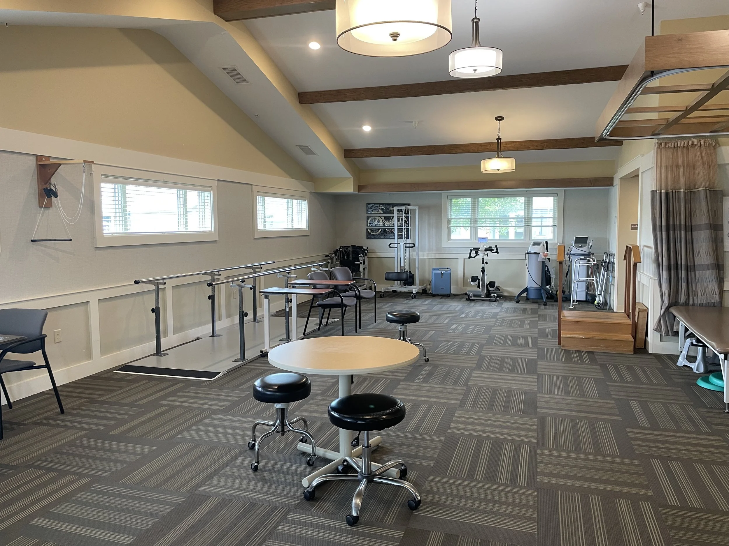 Spacious therapy gym at Fieldstone Nursing and Rehabilitation Center equipped with parallel bars, rehab equipment, and exercise stations for physical and occupational therapy.