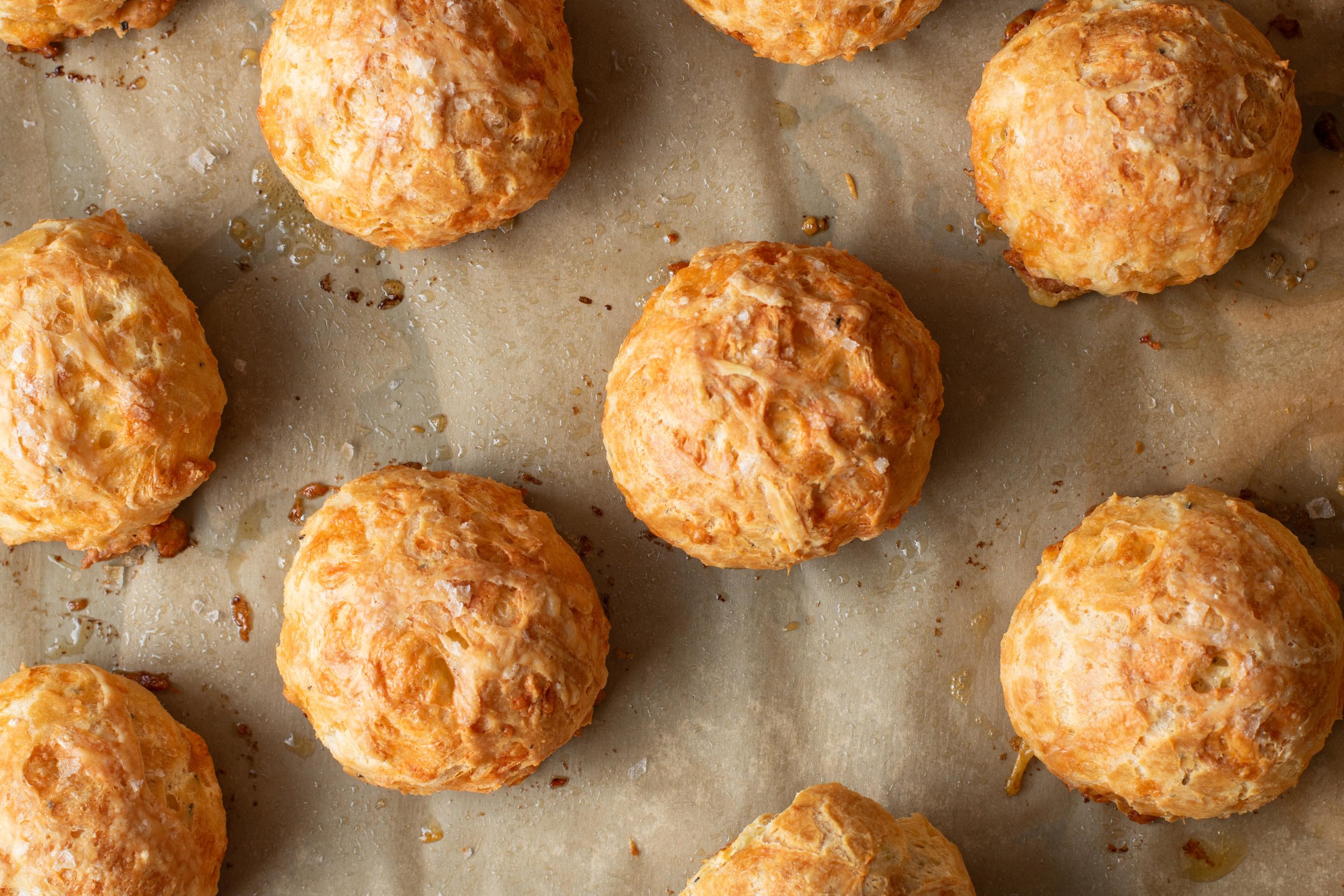 Baked cheese bread rolls on parchment paper.