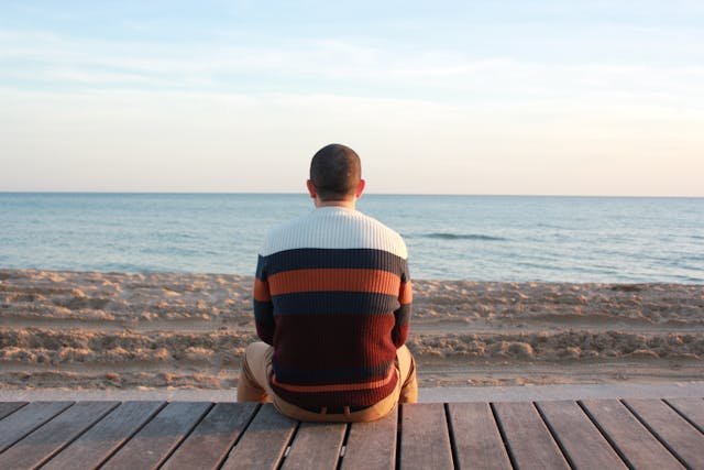 a man sitting on a dock by himself looking at the water
