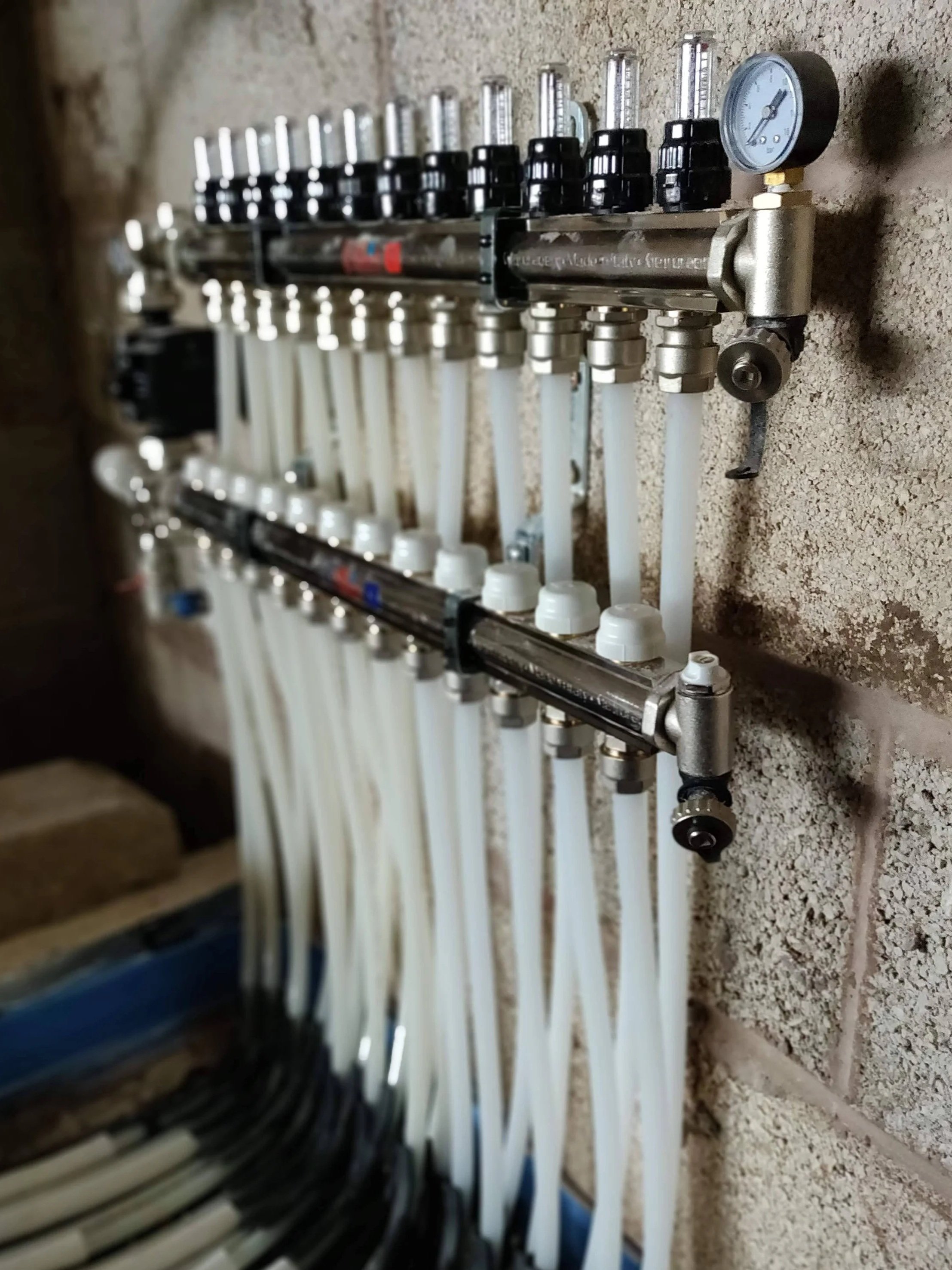 A plumbing manifold with various pipes and gauges mounted on a wall in East Midlands.